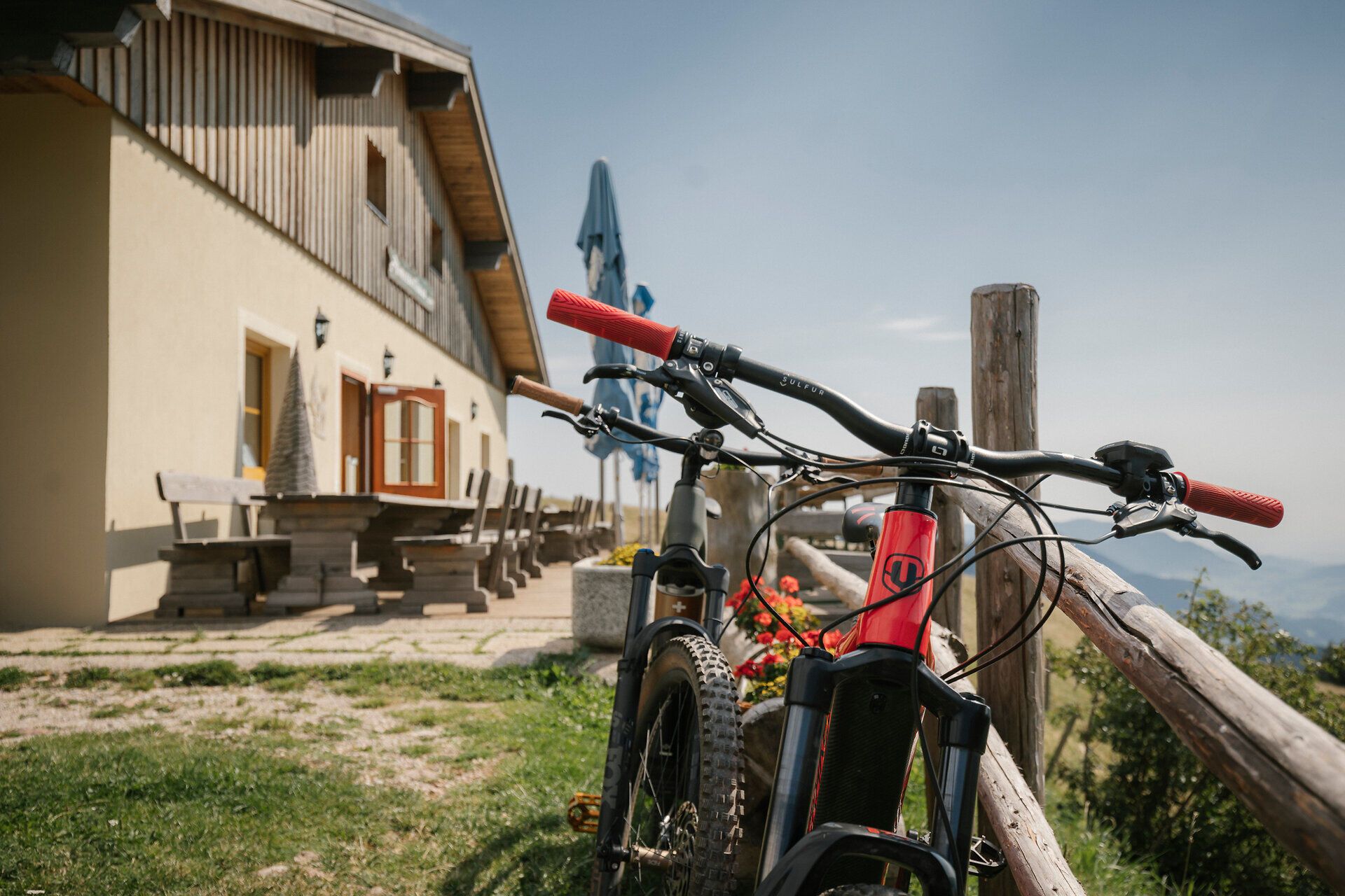 A mountain bike in front of the Almreserlhaus on the Schneeberg, with benches in the background