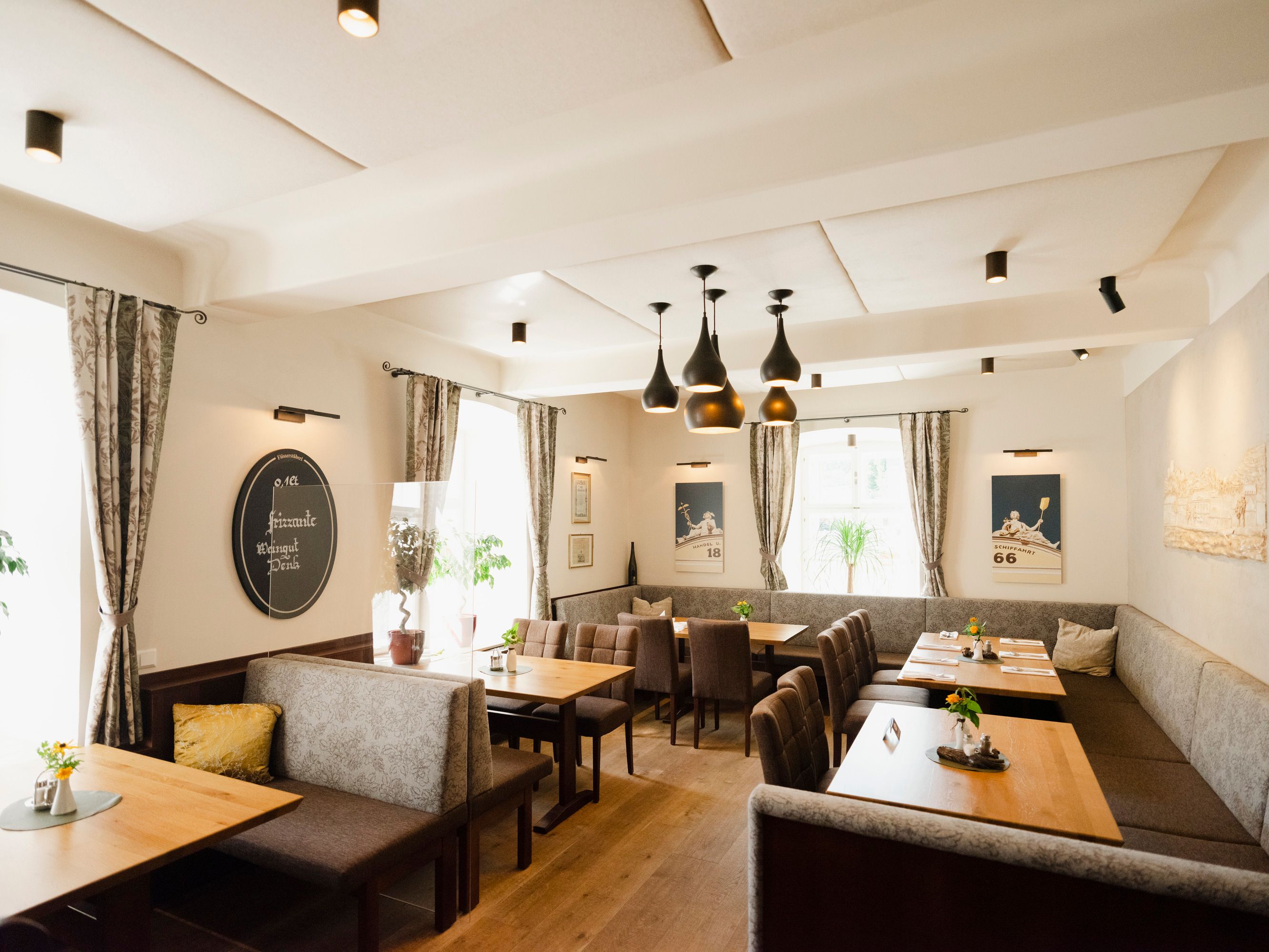 Modern restaurant with wooden tables, gray upholstered benches and stylish lamps.