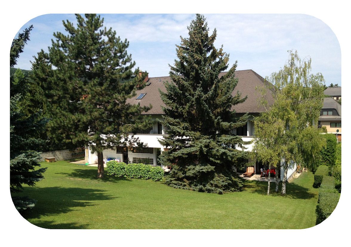 Rear view of an inn with garden and trees.