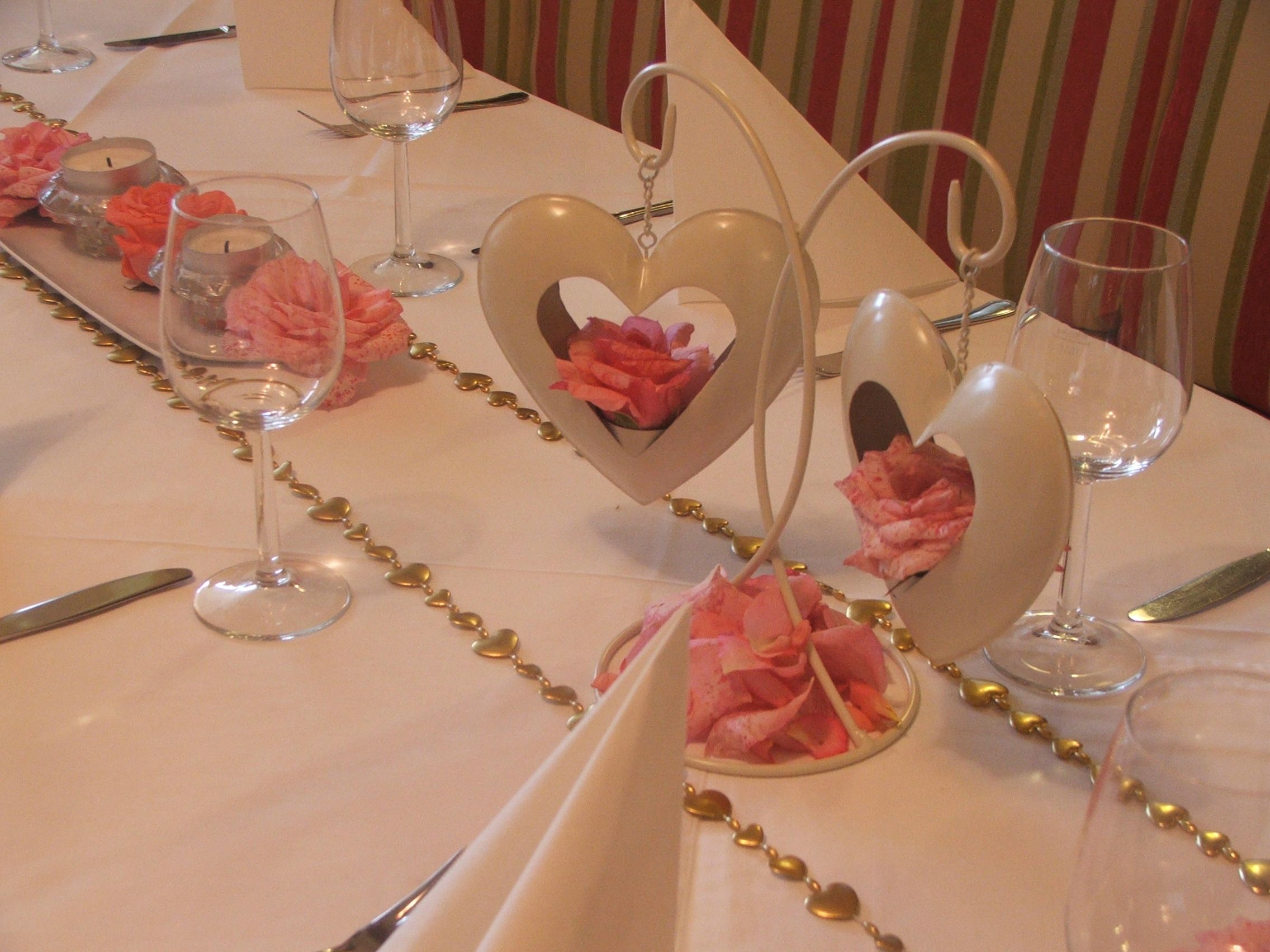 Festively laid table with heart decorations and rose petals.