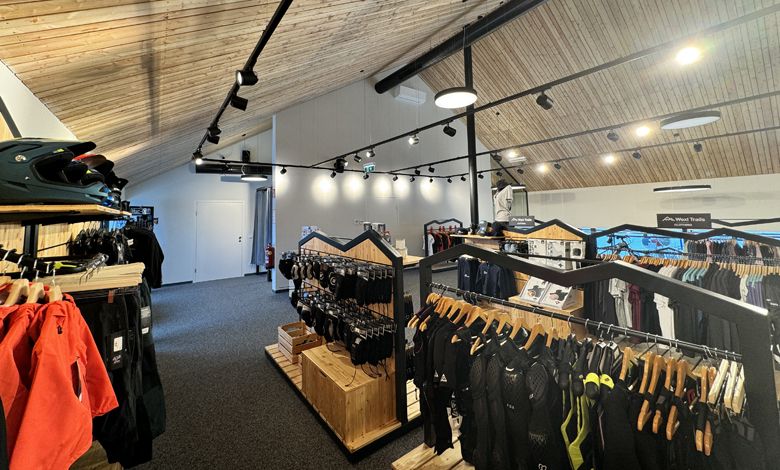 Interior view of a sports store with wooden ceiling and clothes on racks.