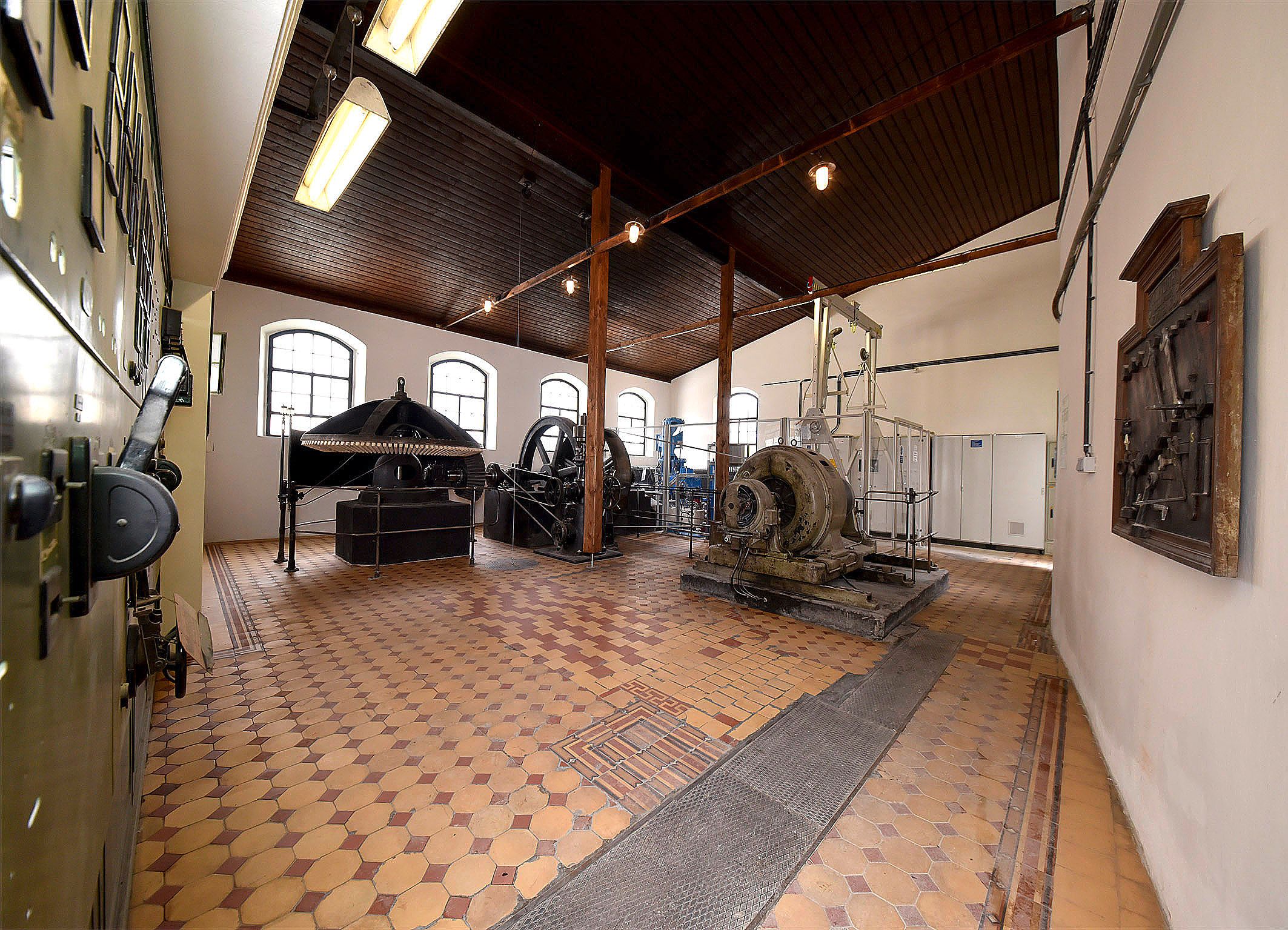 Interior view of a historic power station with machines and equipment.