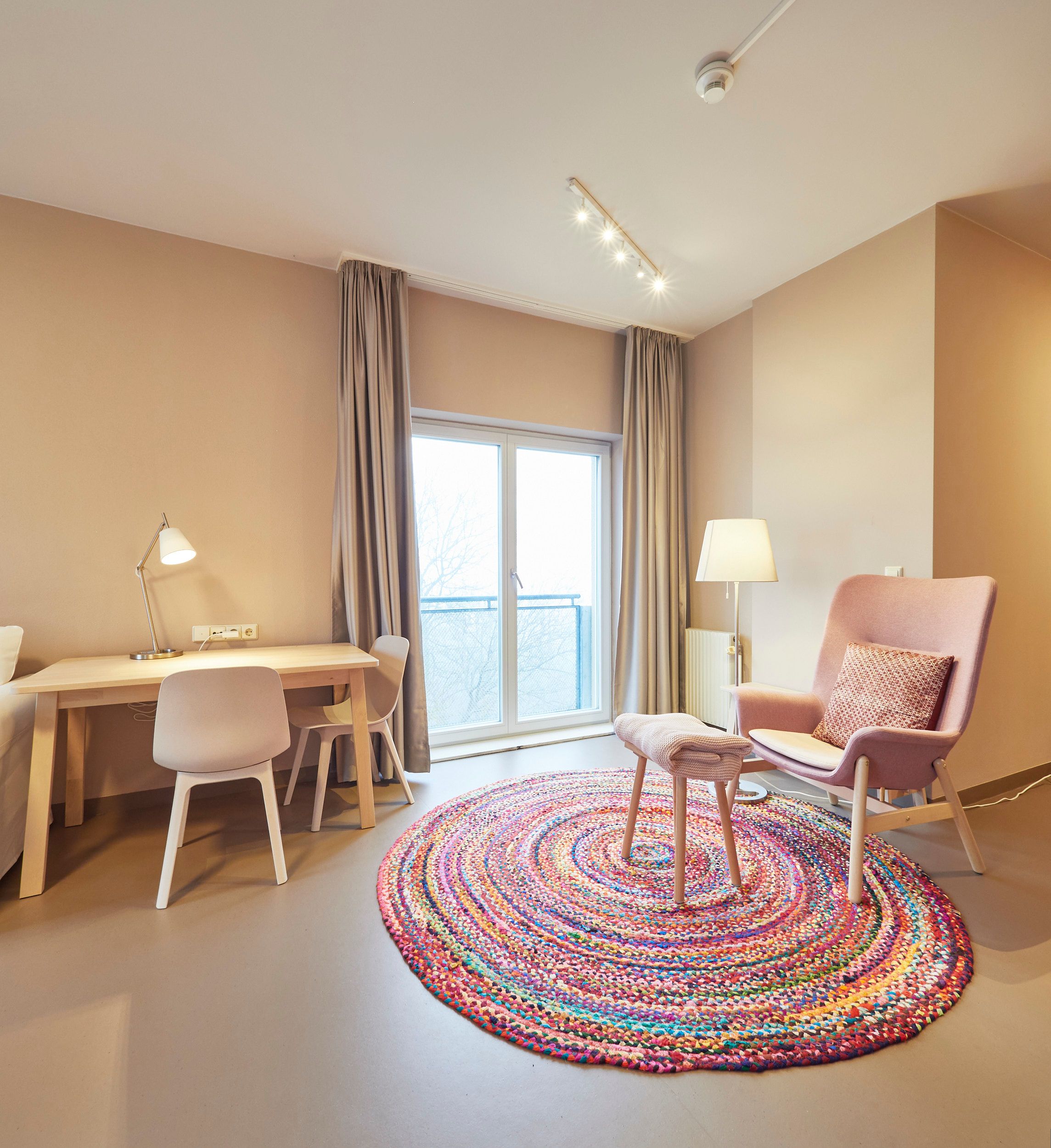 Bright room with desk, chair, armchair and colorful carpet.