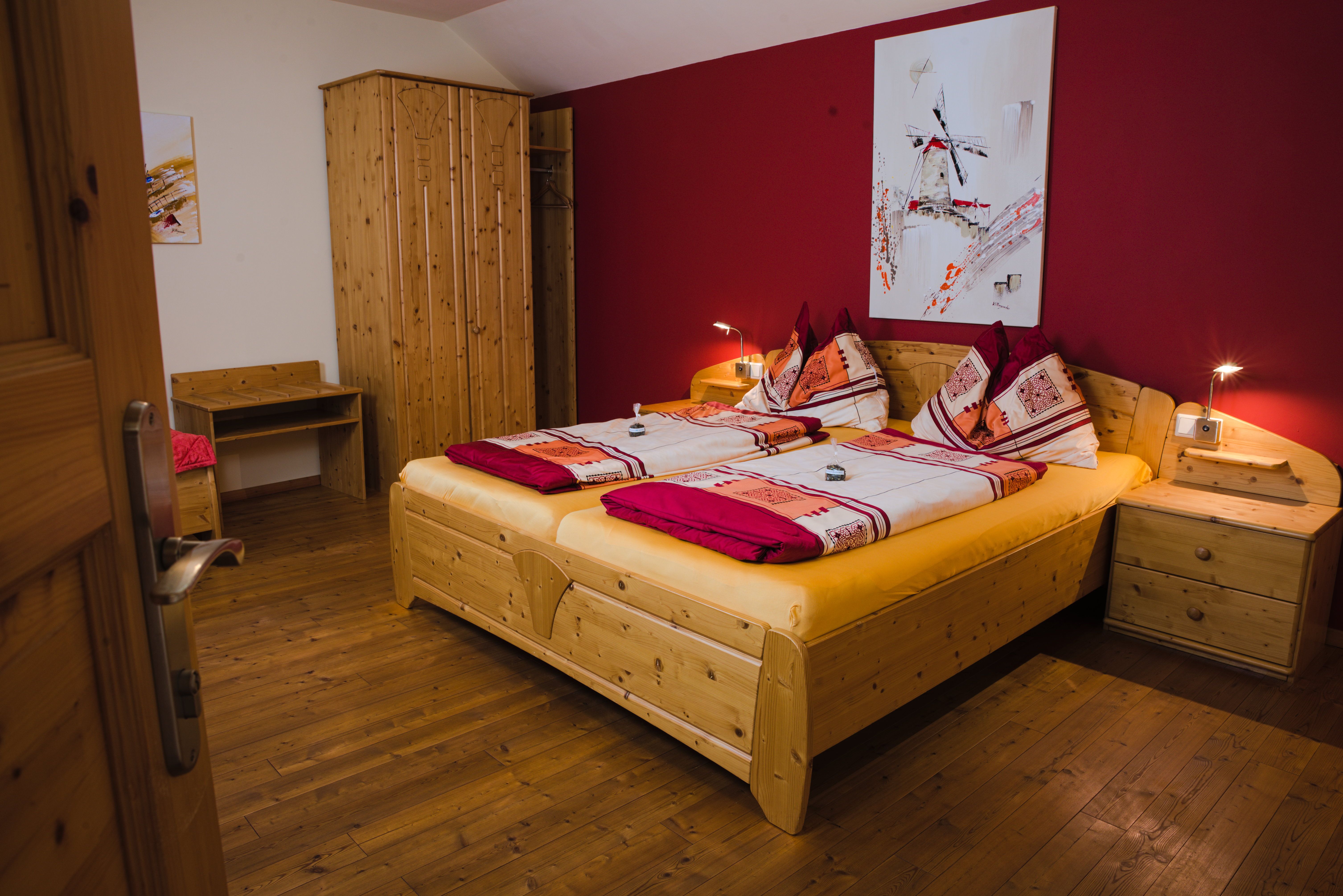 Cozy guest room with double bed, wooden furniture and red wall.