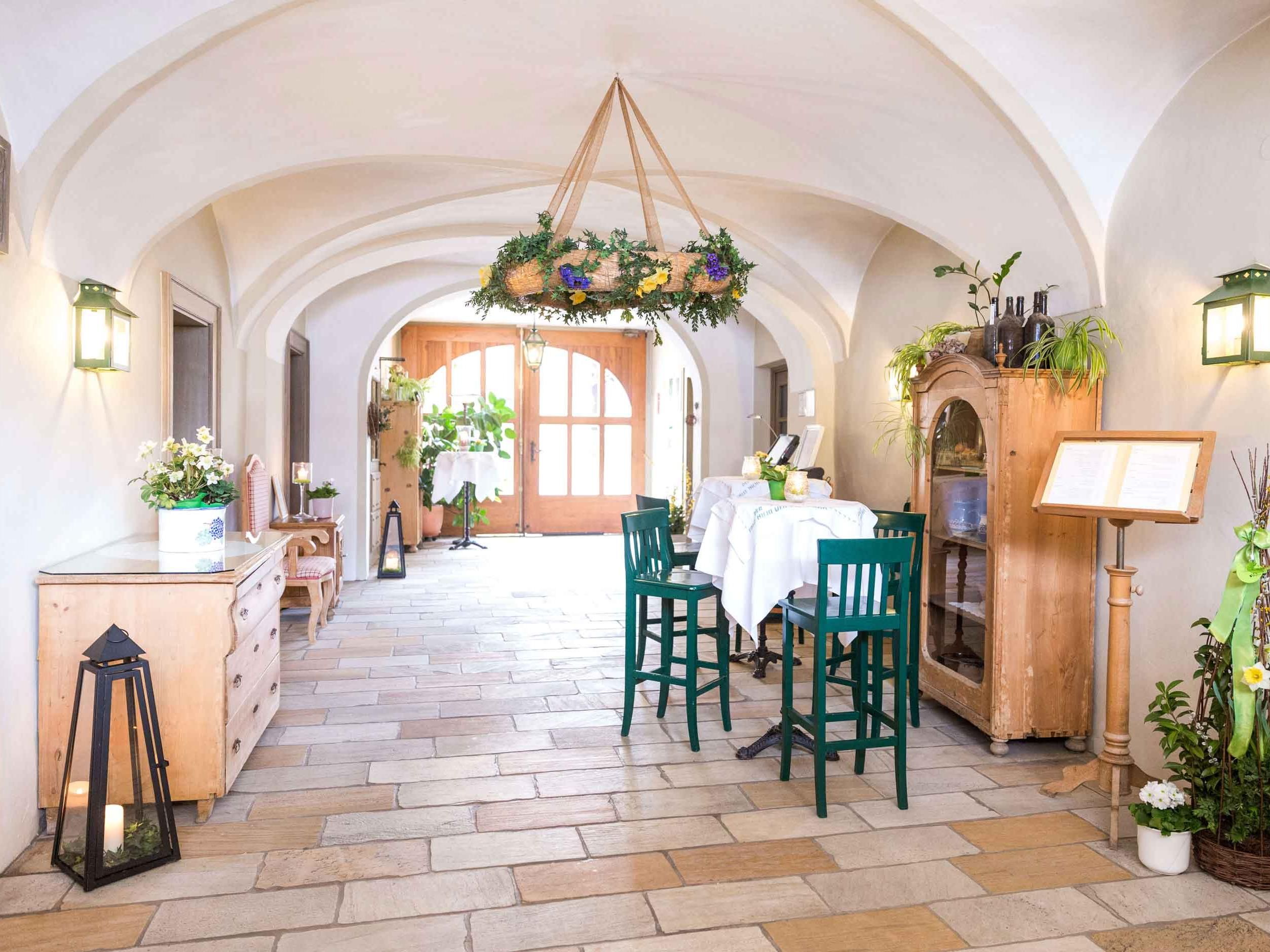 Entrance area of the Loibnerhof with wooden furniture and plants.