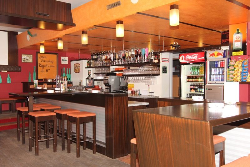 Interior view of a bar with wooden furniture, bar stools and drinks.