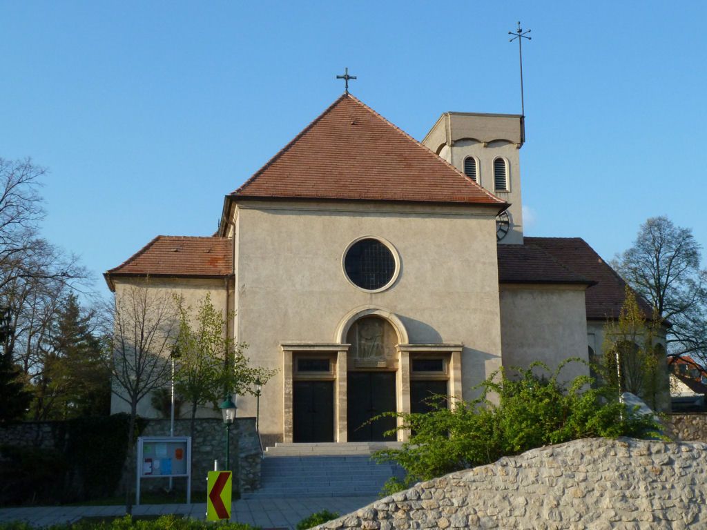 Front view of a church with a red roof and round window.