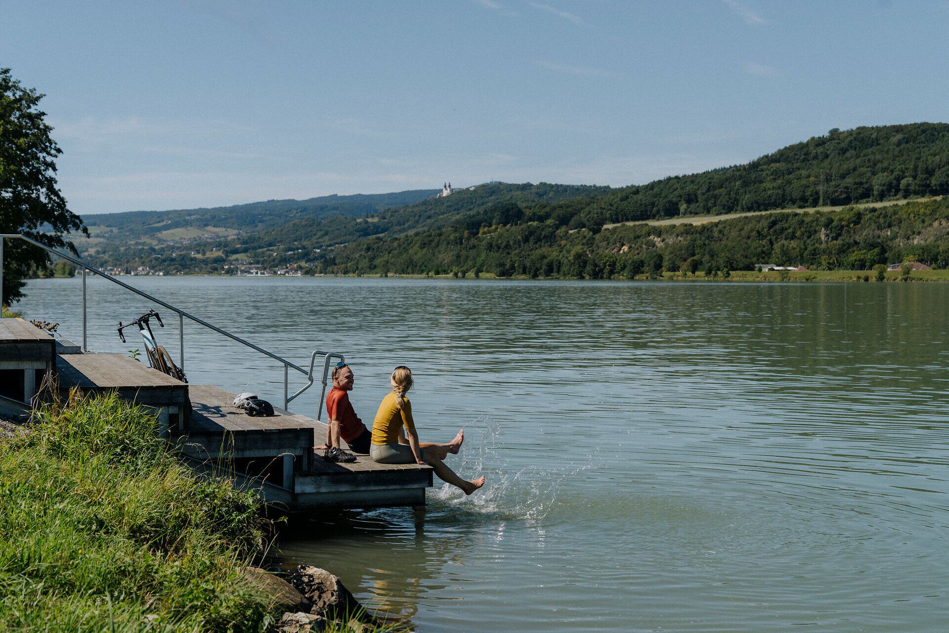 2 cyclists take a break at the Zehenbad on the Danube in Pöchlarn with a view of the Danube and the Nibelungengau region