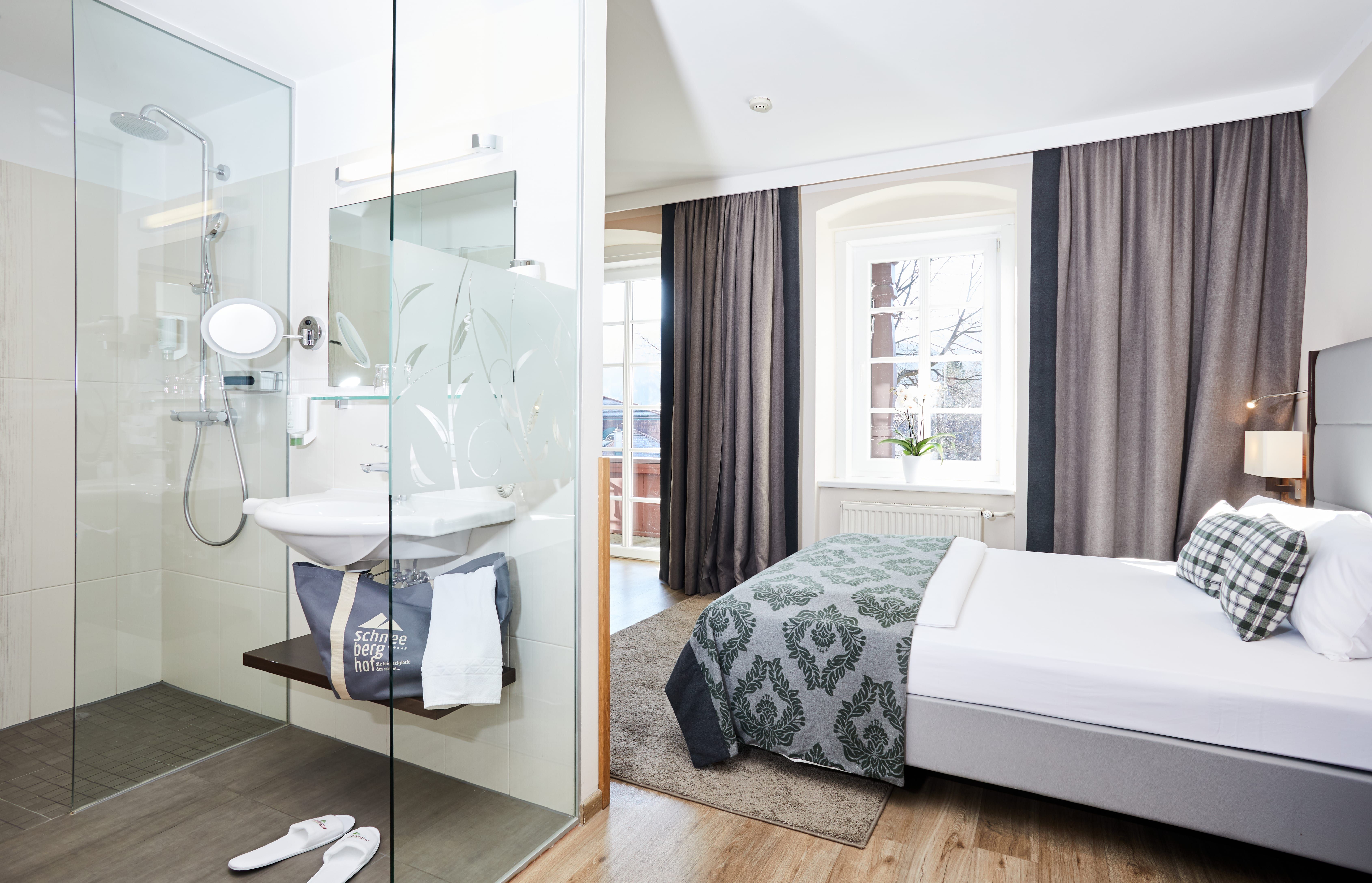 Modern hotel room with double bed and glass shower.