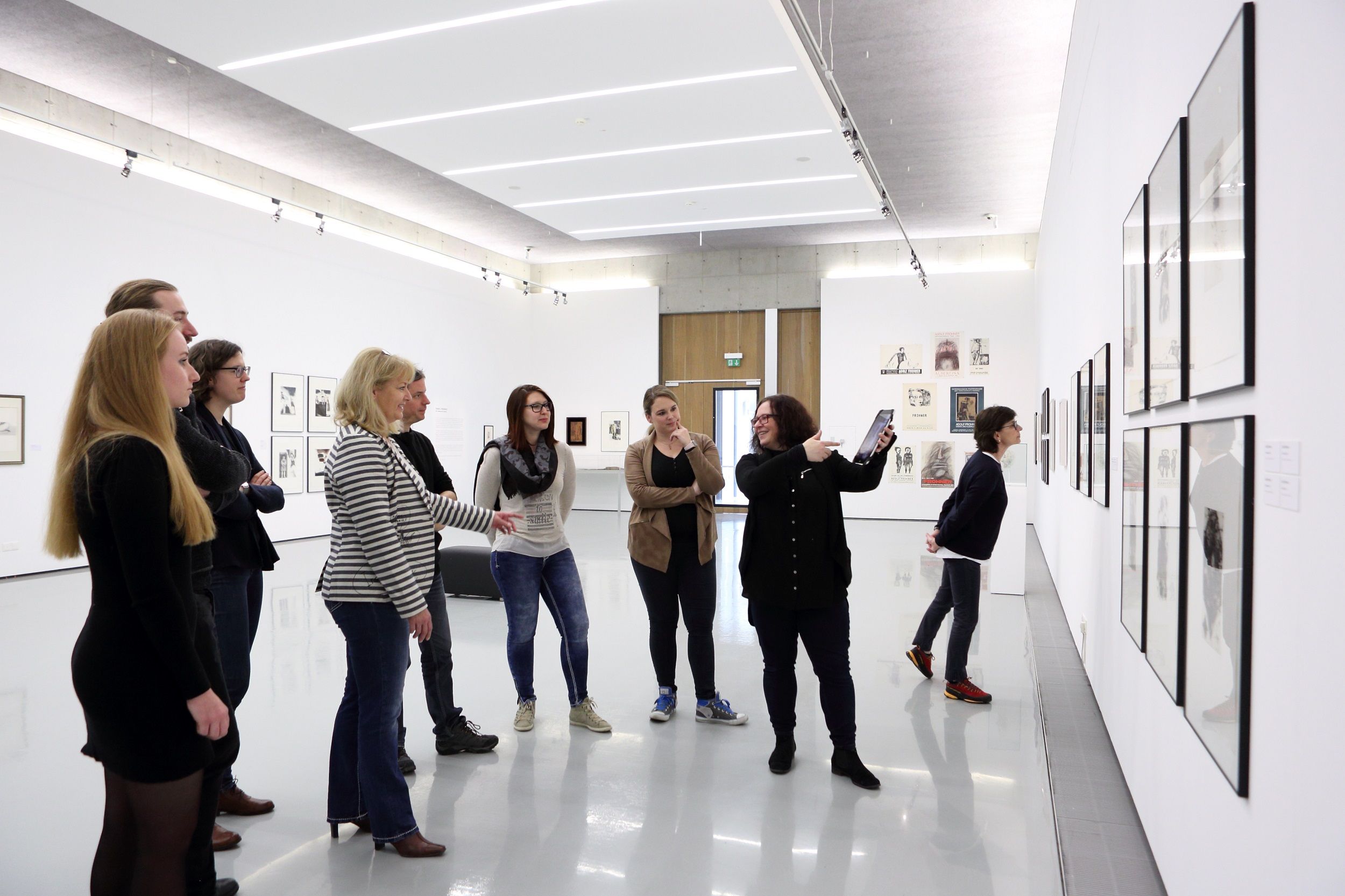 Group of people in an art gallery looking at works of art on the wall.
