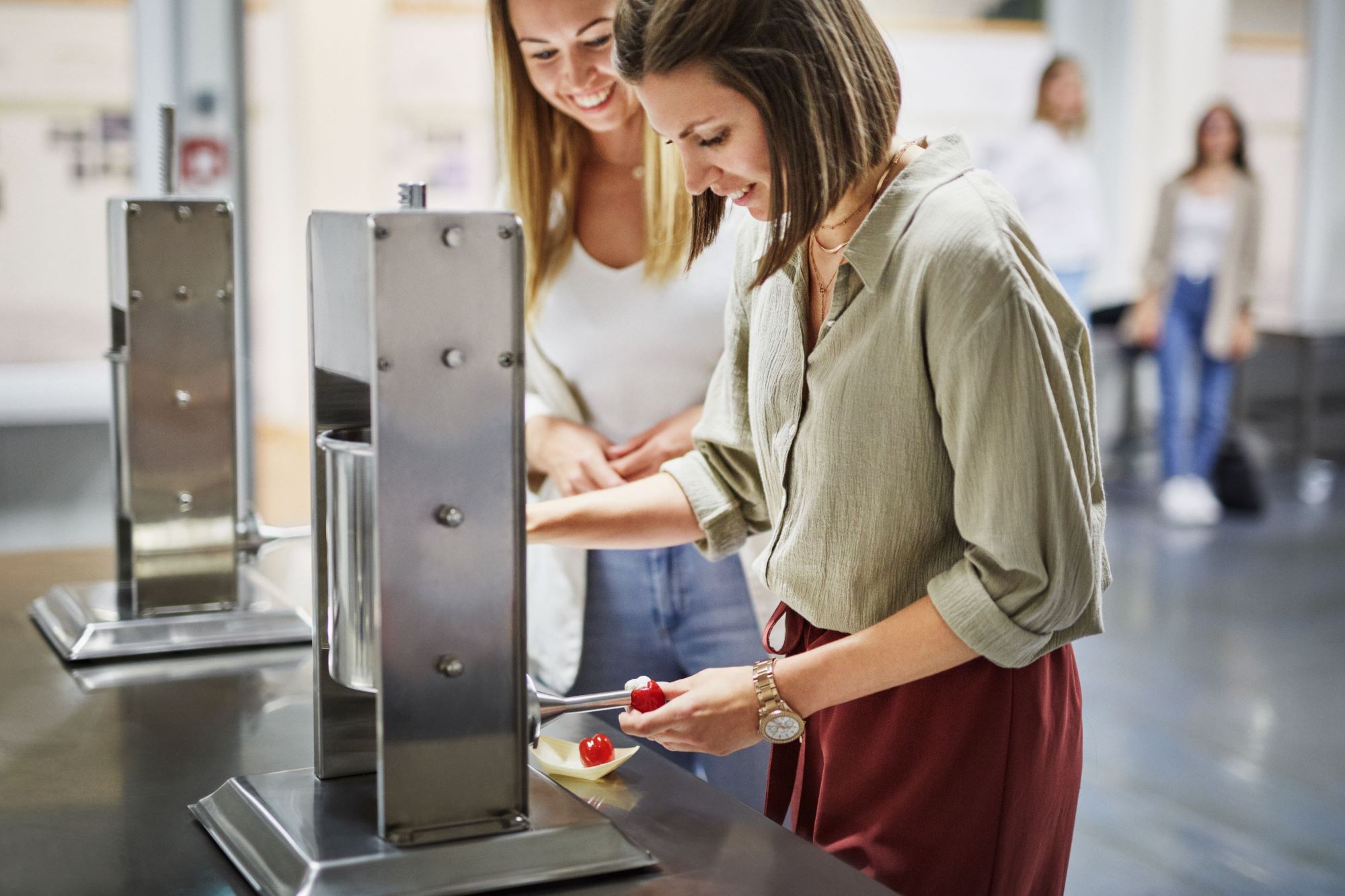 Two women fill Peppersweet with a machine in a kitchen.