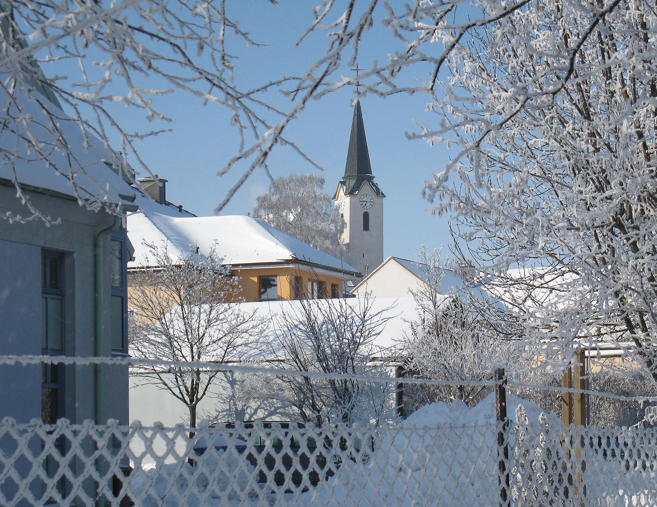 Snowy village view with church and trees in winter.
