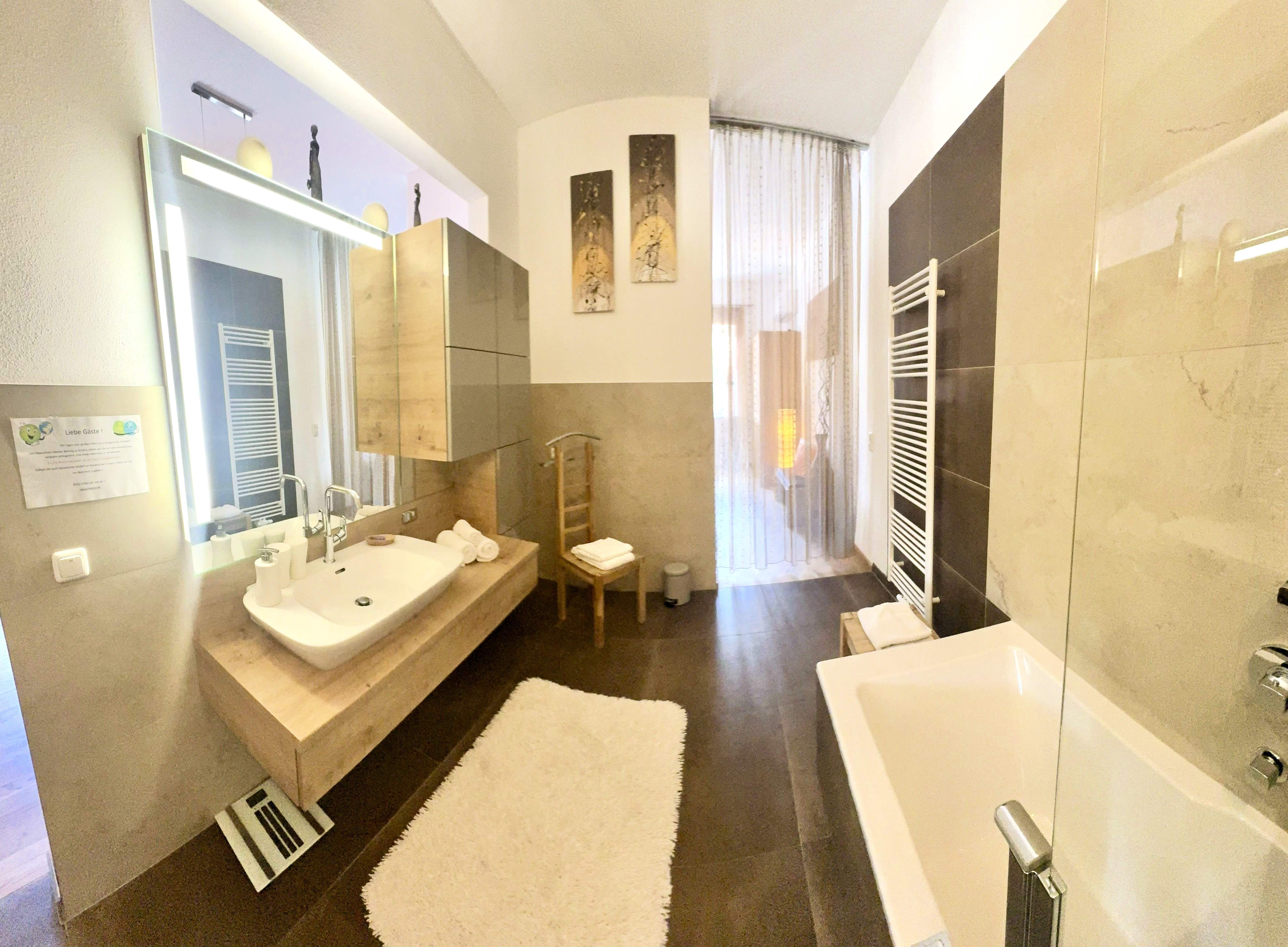 Modern bathroom with a bathtub, sink, and large mirror.