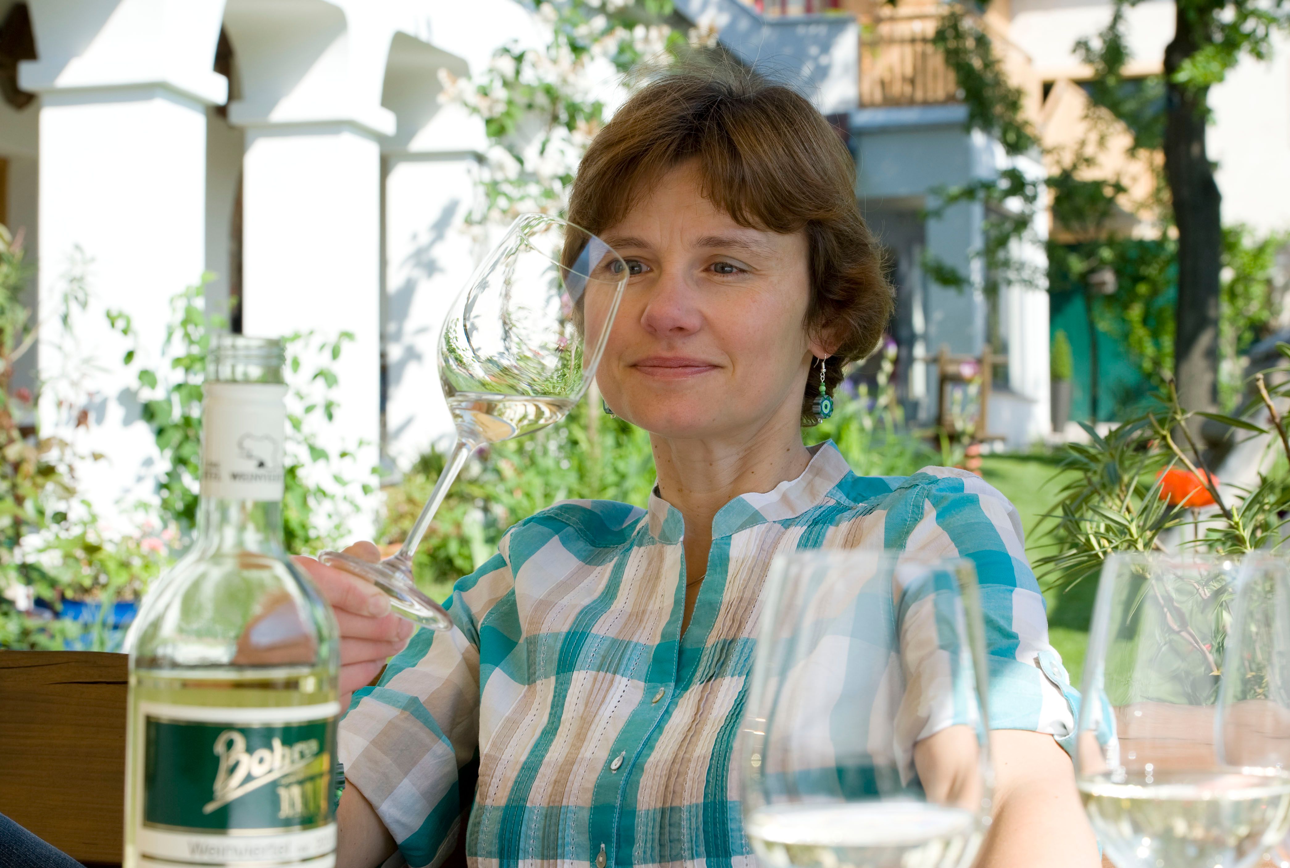 Woman with wine glass in the garden, bottle in the foreground.