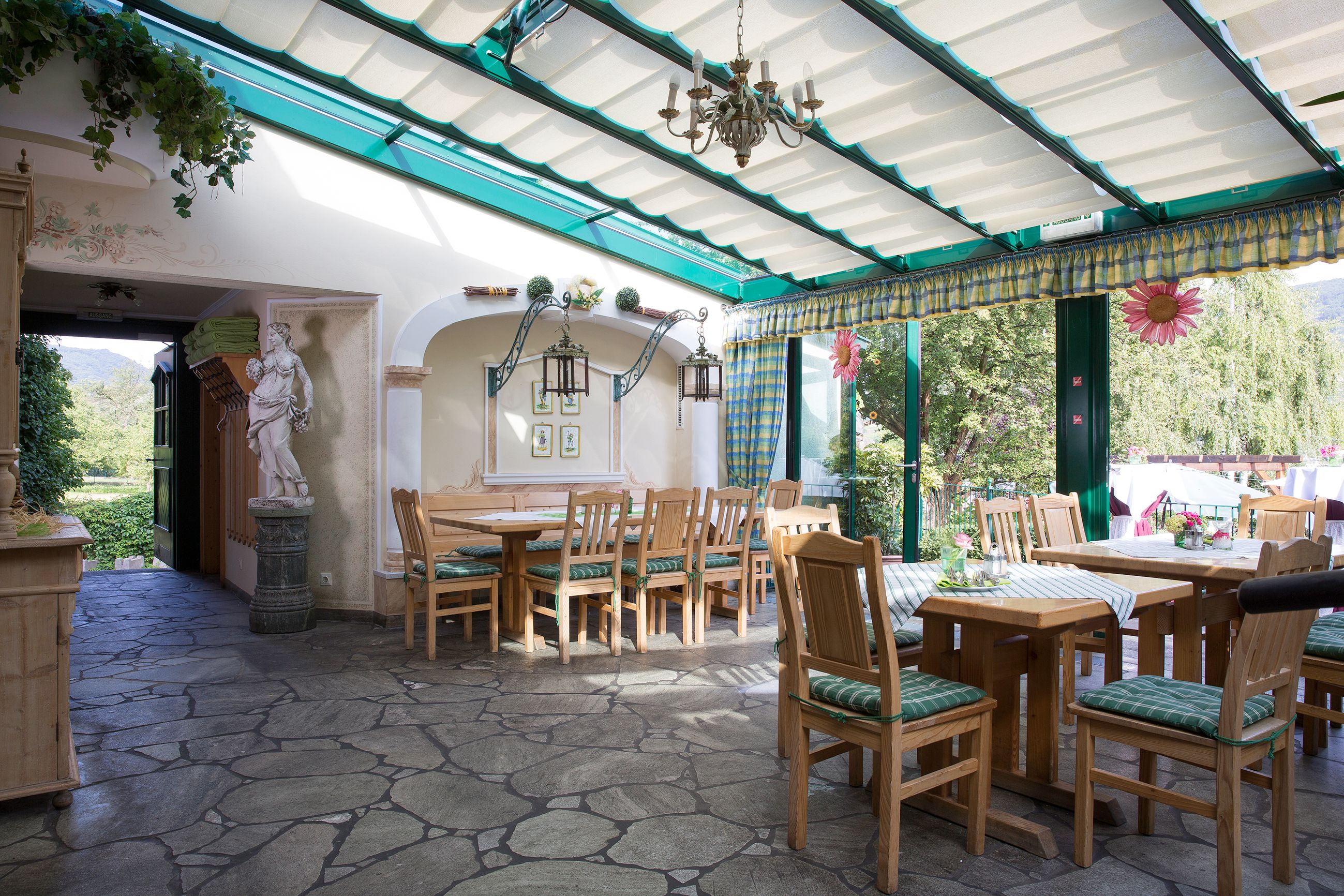 Interior view of a wine tavern with wooden furniture, stone floor and glass roof.