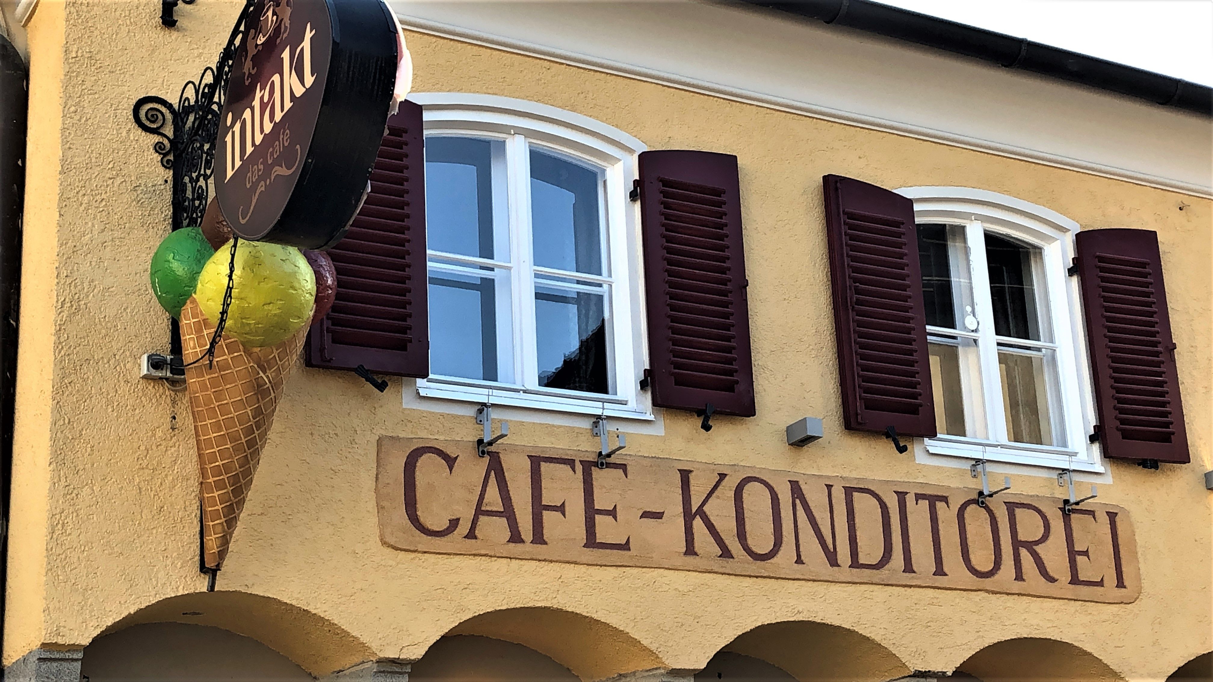 Facade of a café with ice cream cone decoration and 'Cafe-Konditorei' lettering.