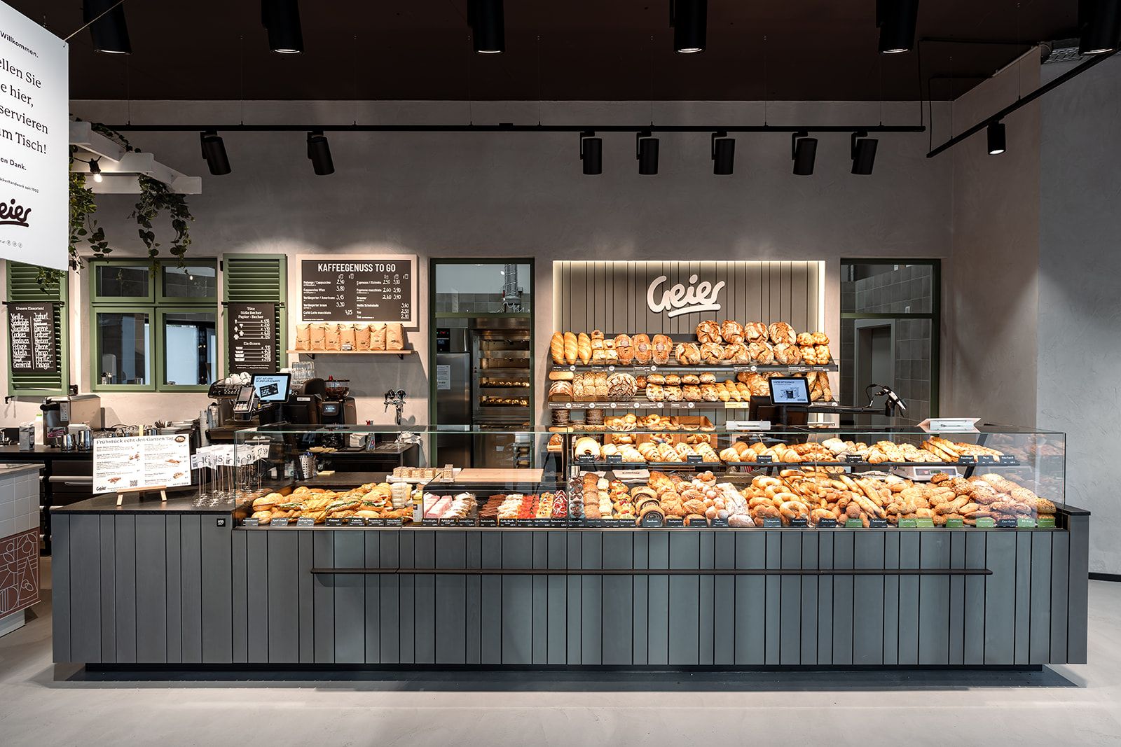 Interior view of a modern bakery with a counter full of baked goods and a sign with the name Geier.