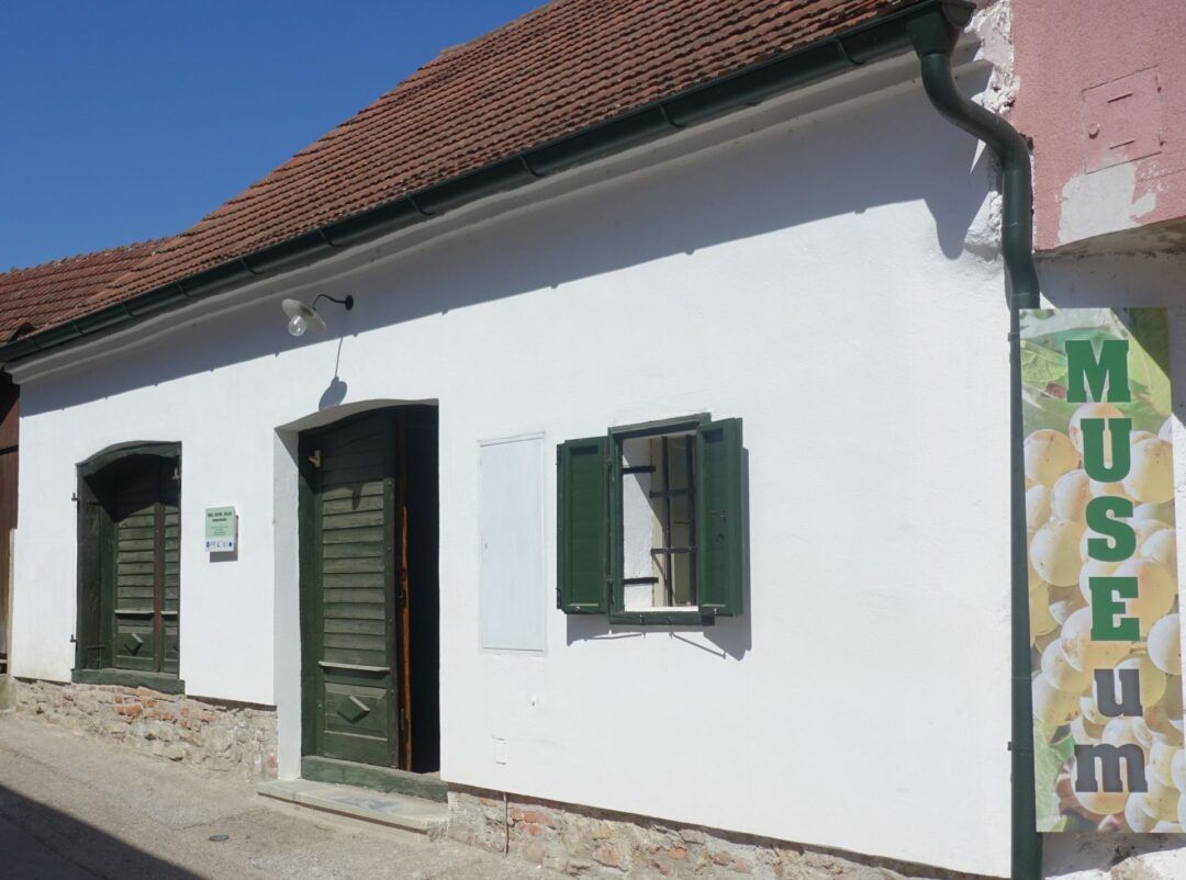 White building with green shutters and door, sign with the inscription 'MUSEUM'.