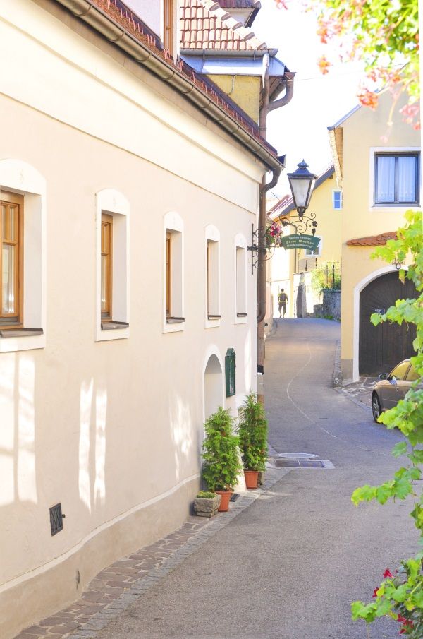 Narrow alley in the Wachau with yellow houses and a lantern.