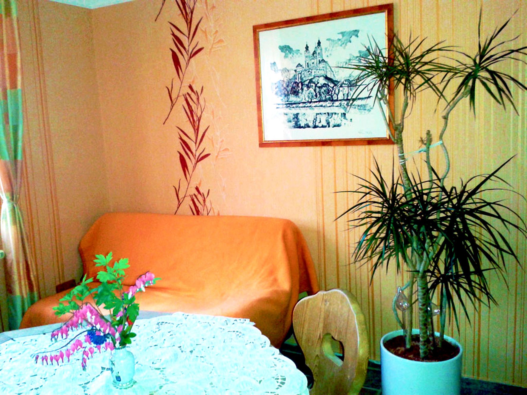 Cozy room with sofa, plant and table with flowers.