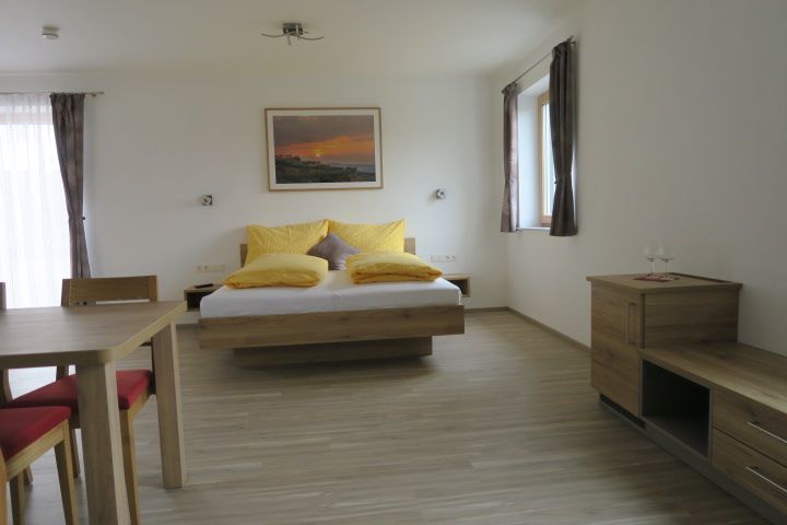 Modern guest room with double bed, wooden furniture and yellow cushions.