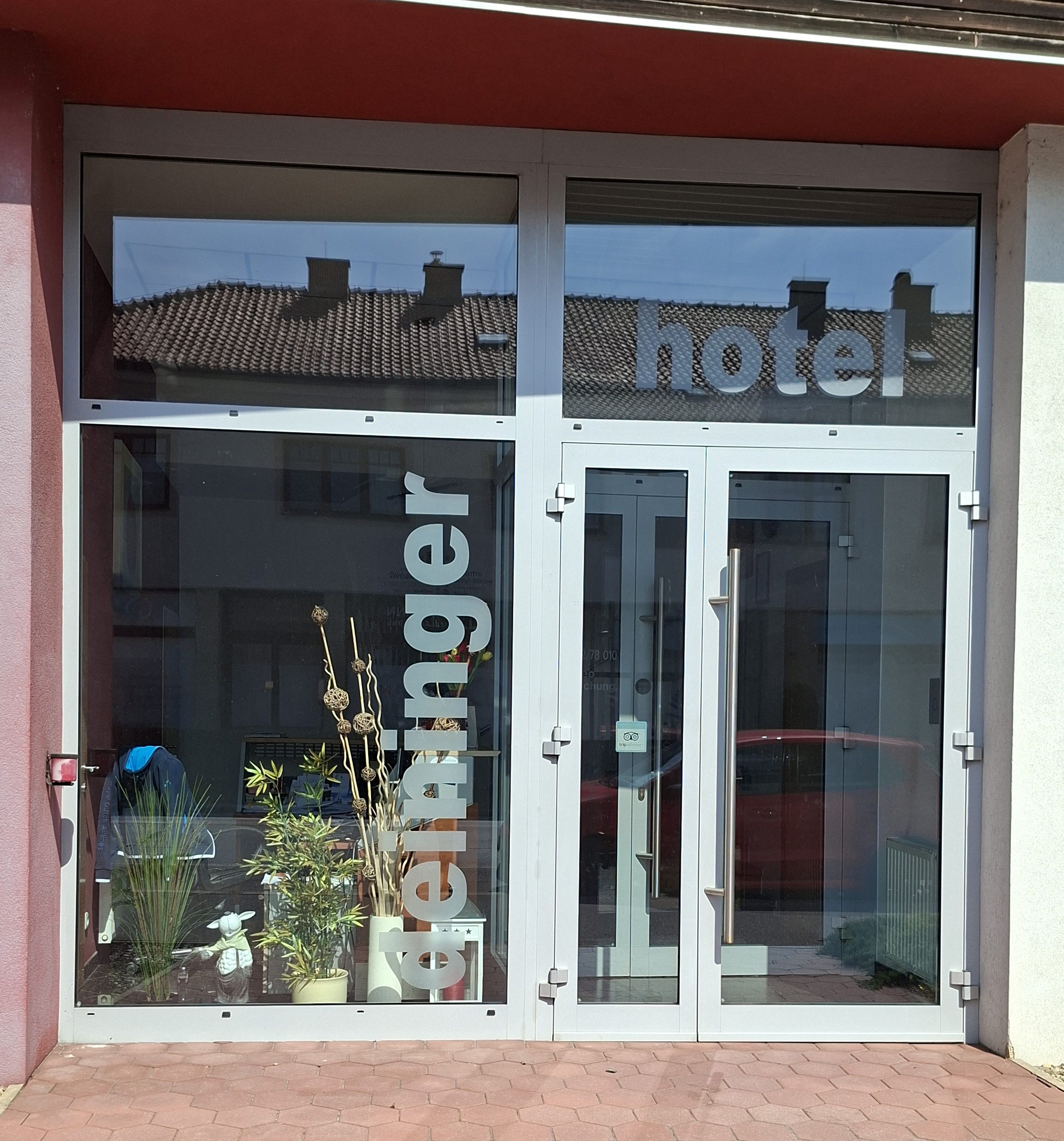 Entrance to the Hotel Deininger with glass front and plants.