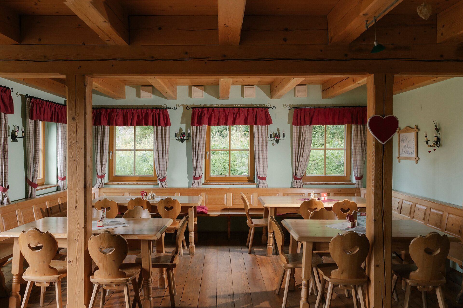 Dining room with wooden tables and curtains at the Hengsthütte on Schneeberg