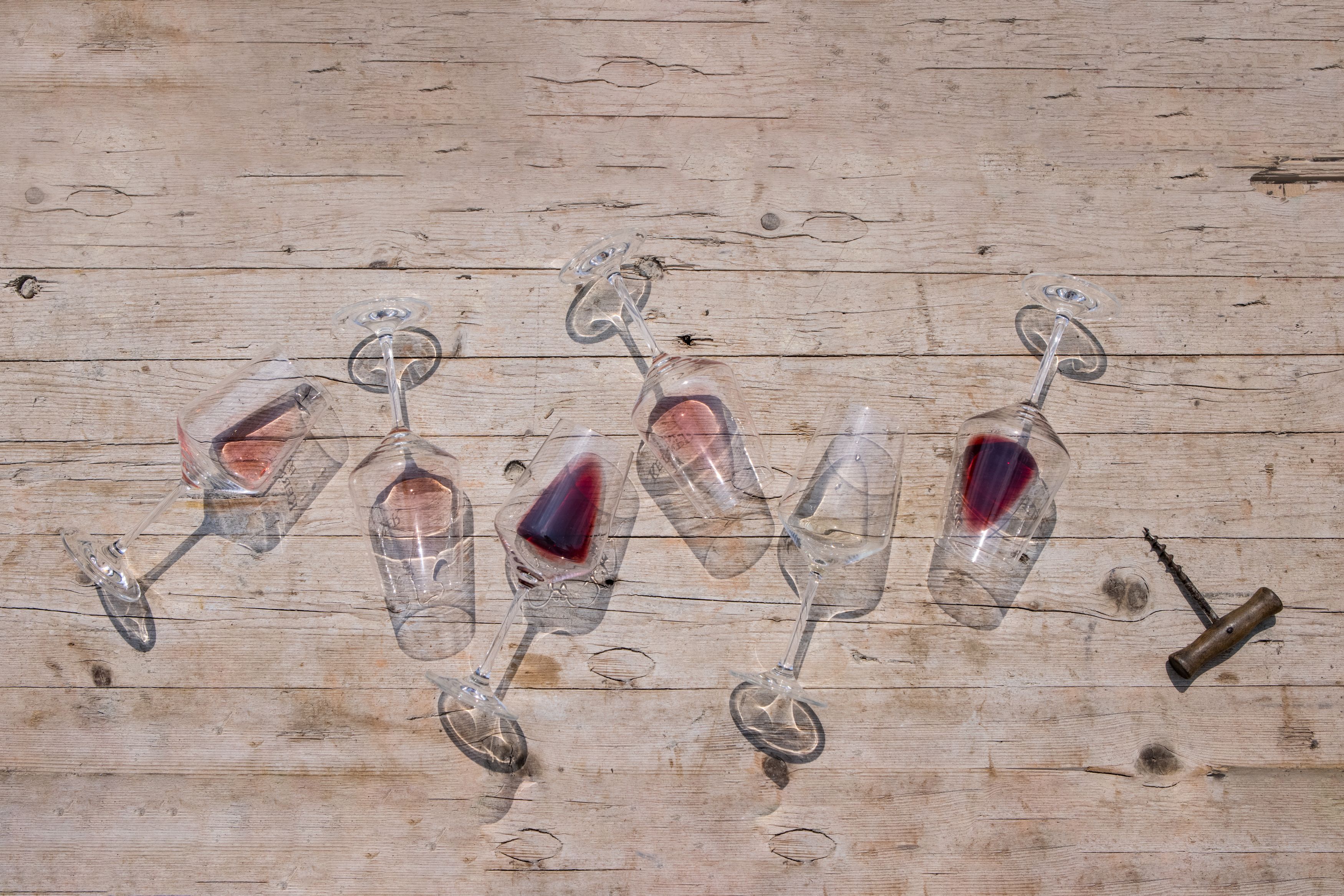 Overturned wine glasses with red wine on a wooden table.