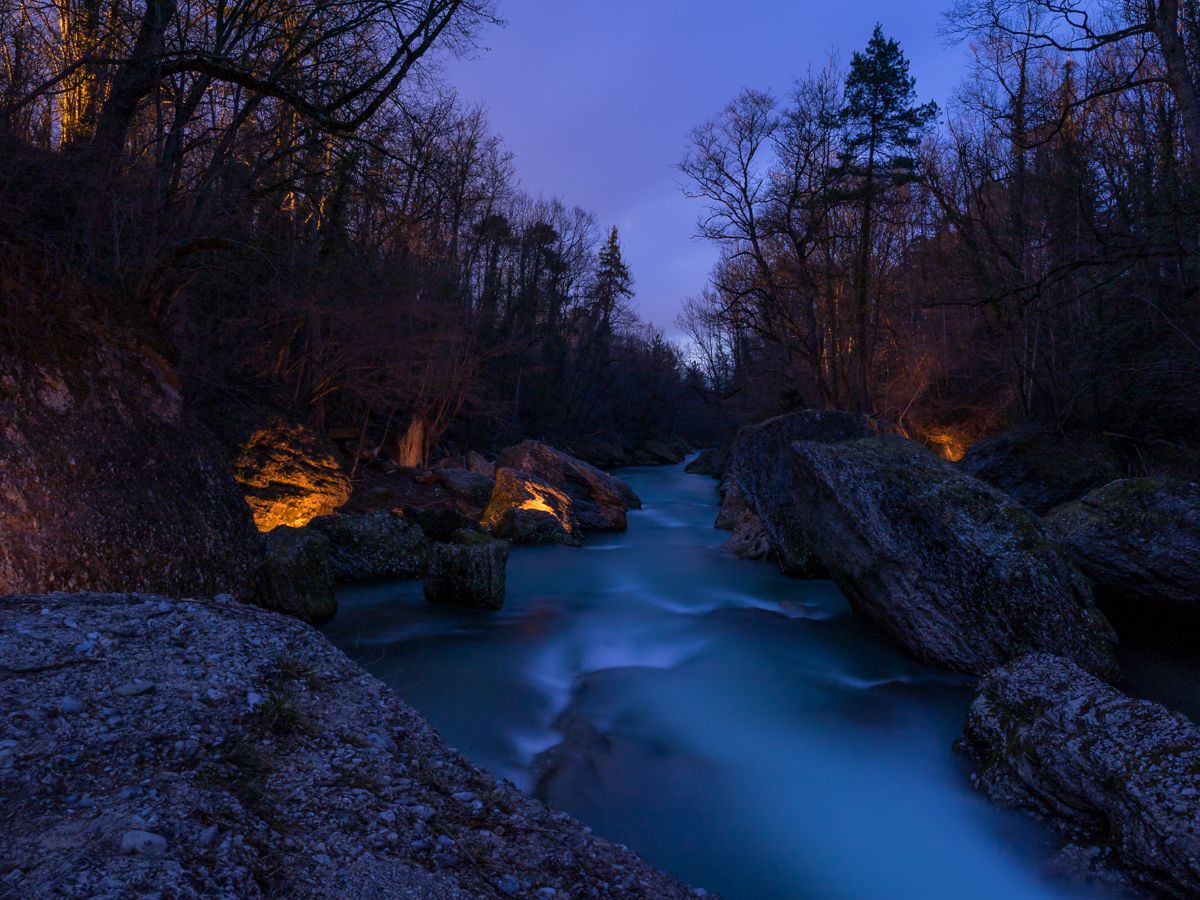 Night shot of the Erlauf Gorge with illuminated rocks and flowing water.
