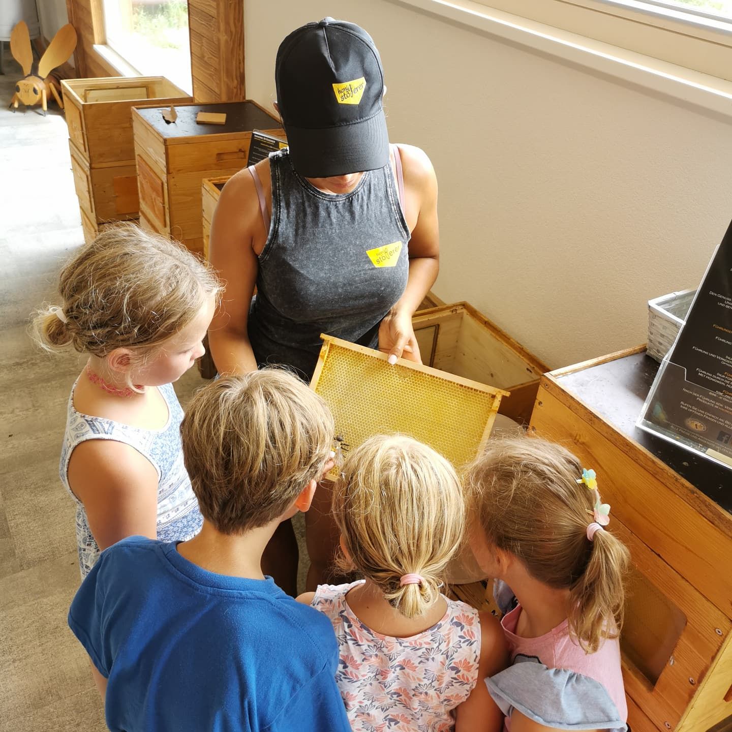 A woman shows children a honeycomb in a beekeeper's store.