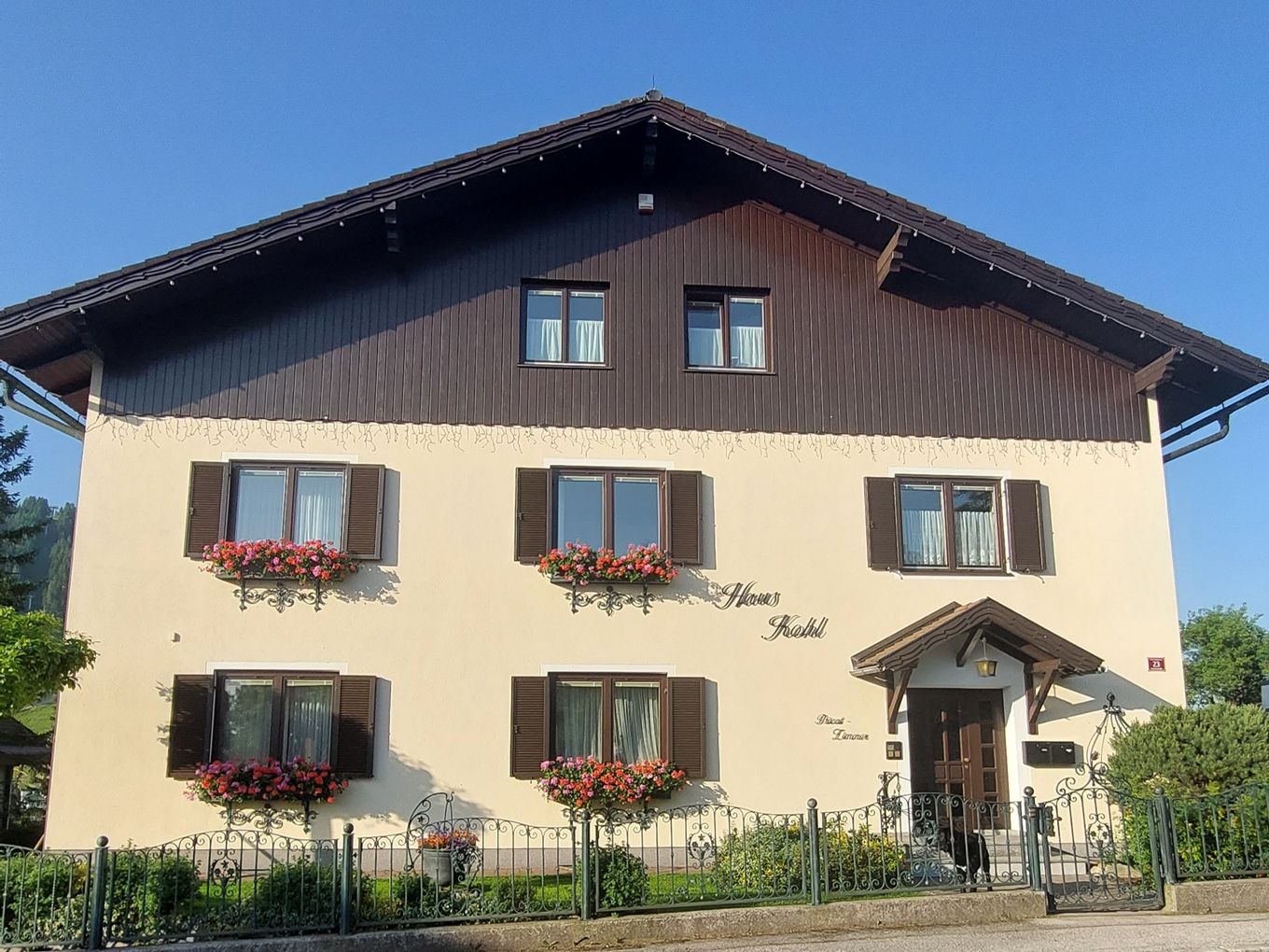 A traditional two-storey house with wooden cladding and flower boxes in front of the windows.