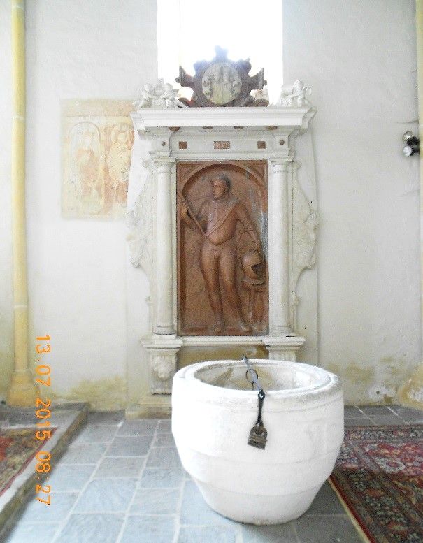 Tomb with relief and baptismal font in a church.