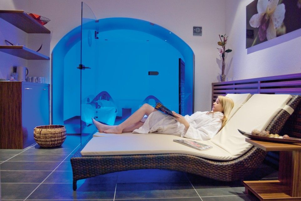 Woman relaxing on a lounger in the wellness area with blue lighting.