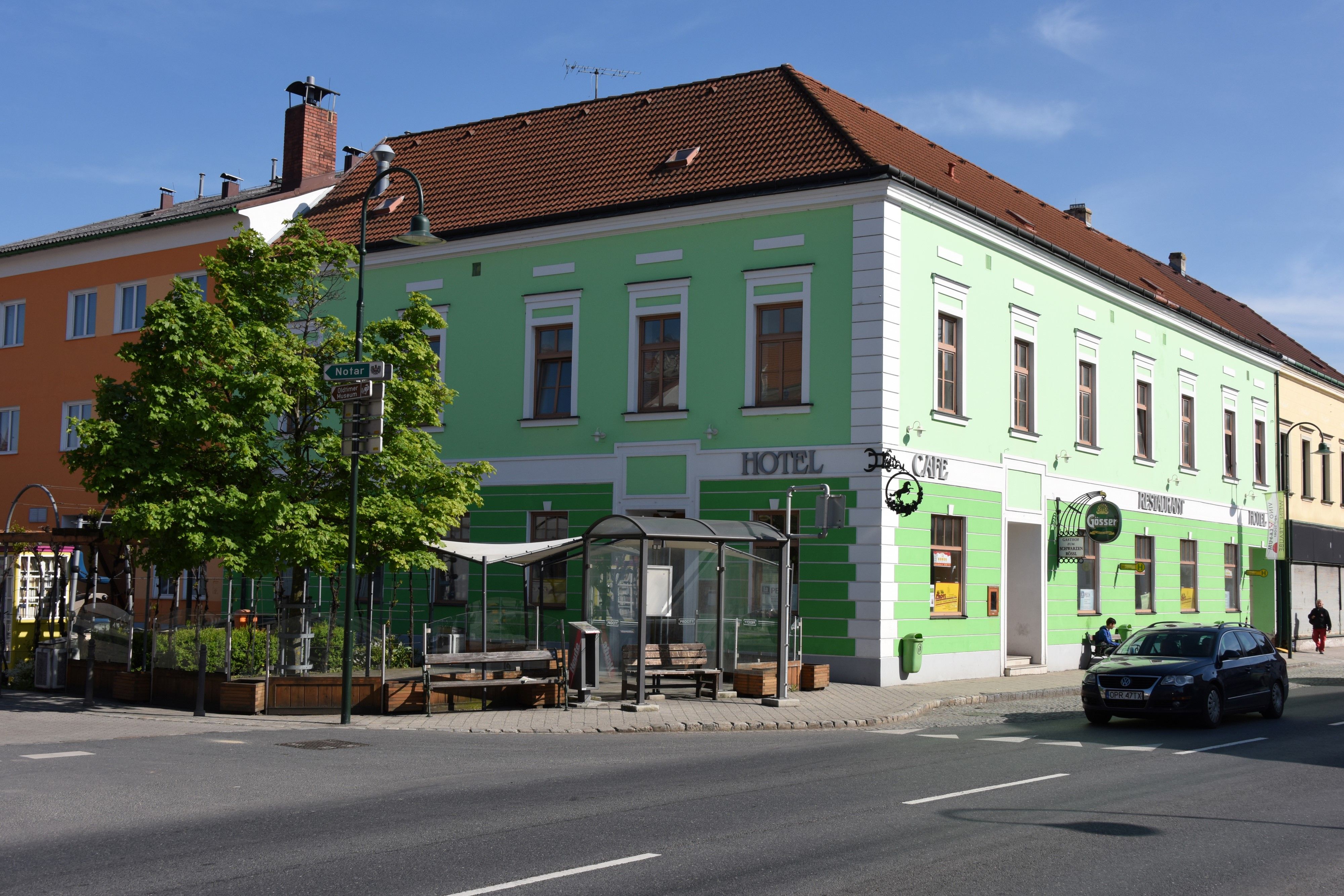 Green building with hotel and café signs on a street corner.