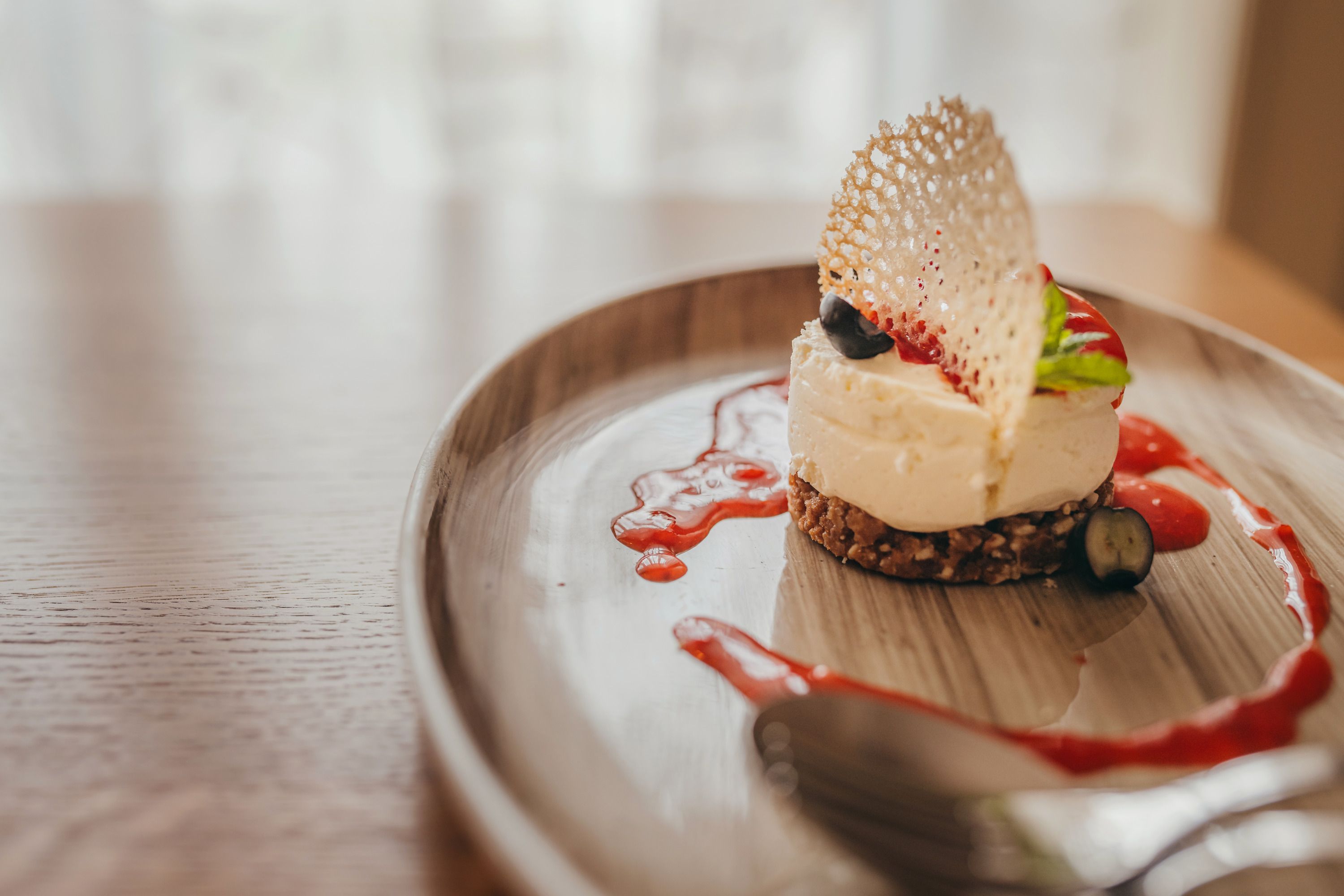 Mini cheesecake with strawberry coulis served on a plate.