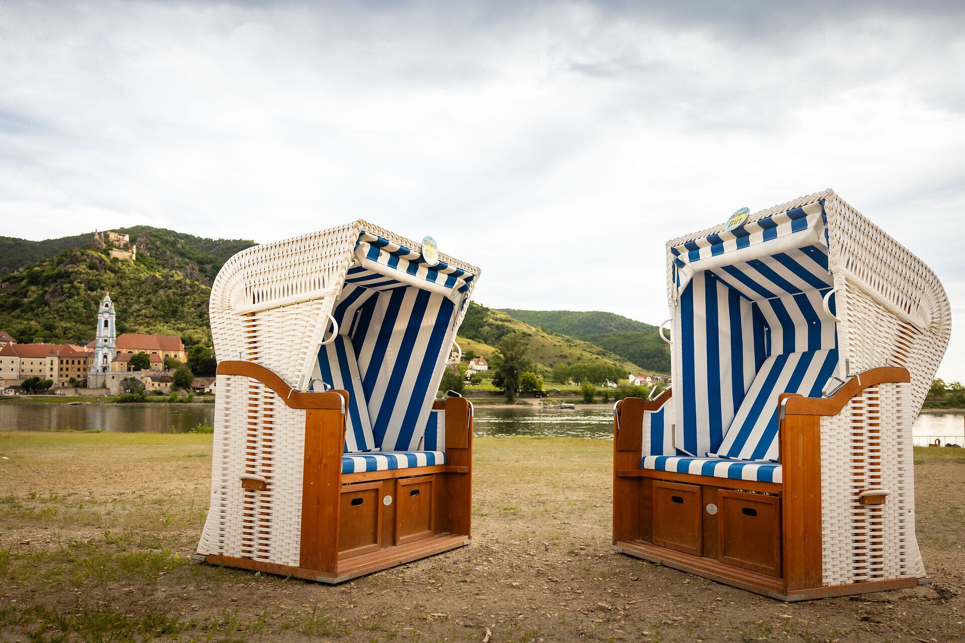 A woman lies on an air mattress in the water, with a view of the town of Dürnstein and the surrounding hills.