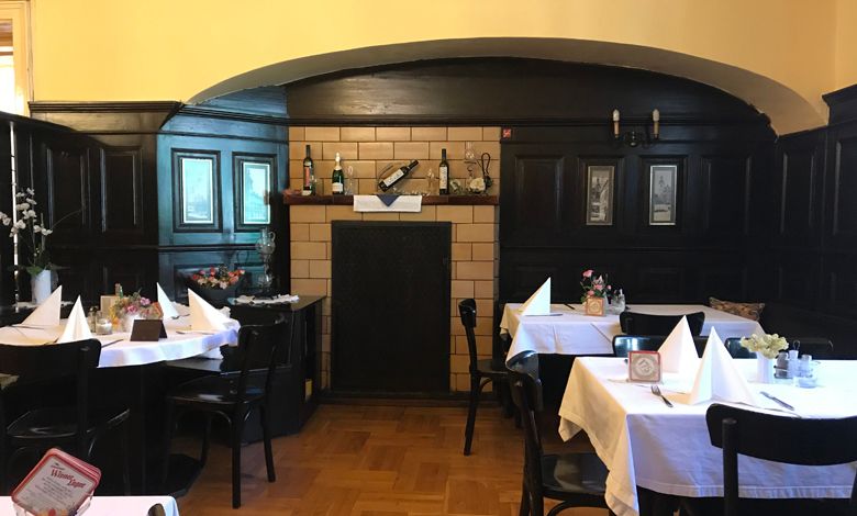 Interior view of a traditional restaurant with dark wood paneling and laid tables.