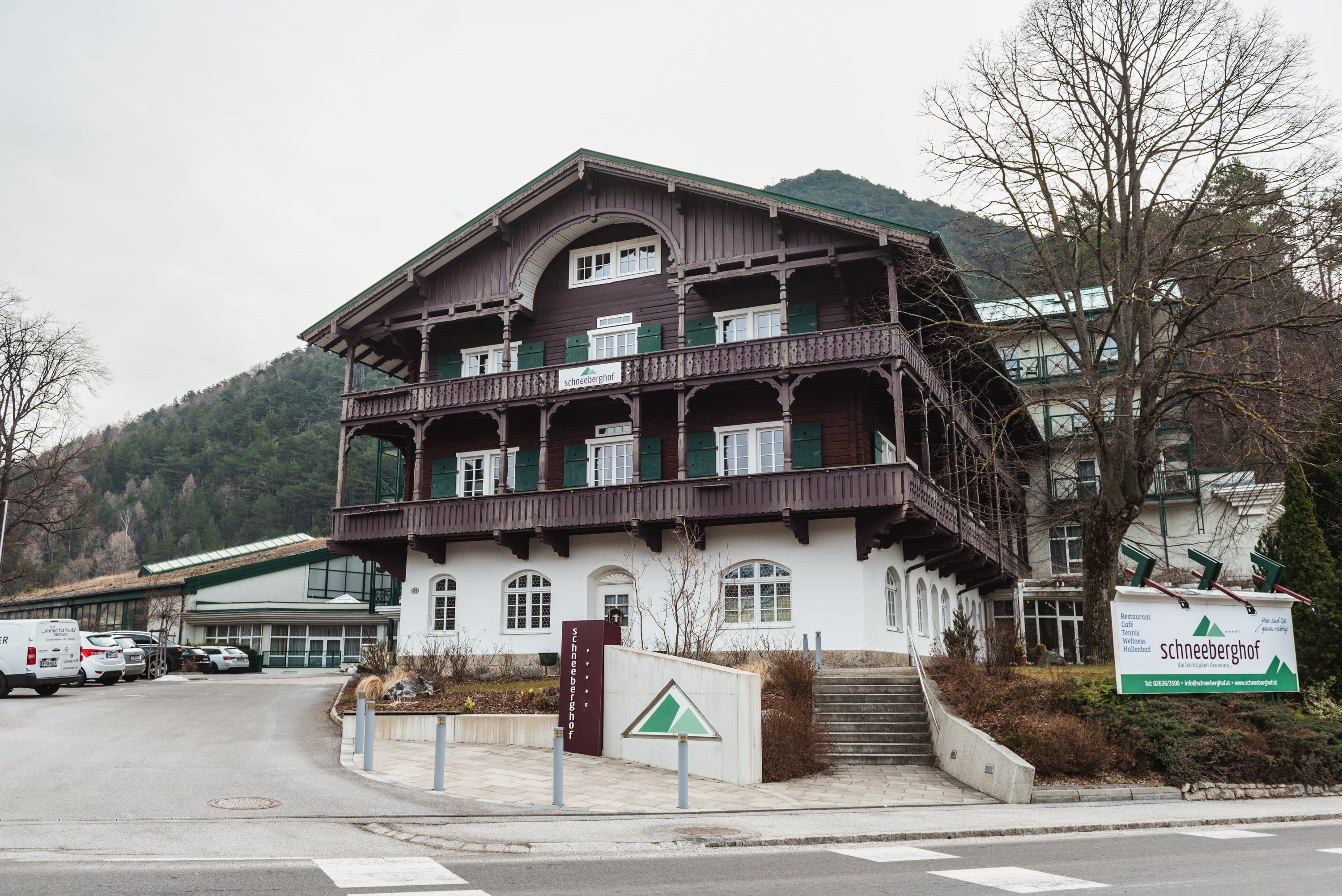 Hotel Schneeberghof in a mountainous setting with traditional architecture and a large sign in front of the building.