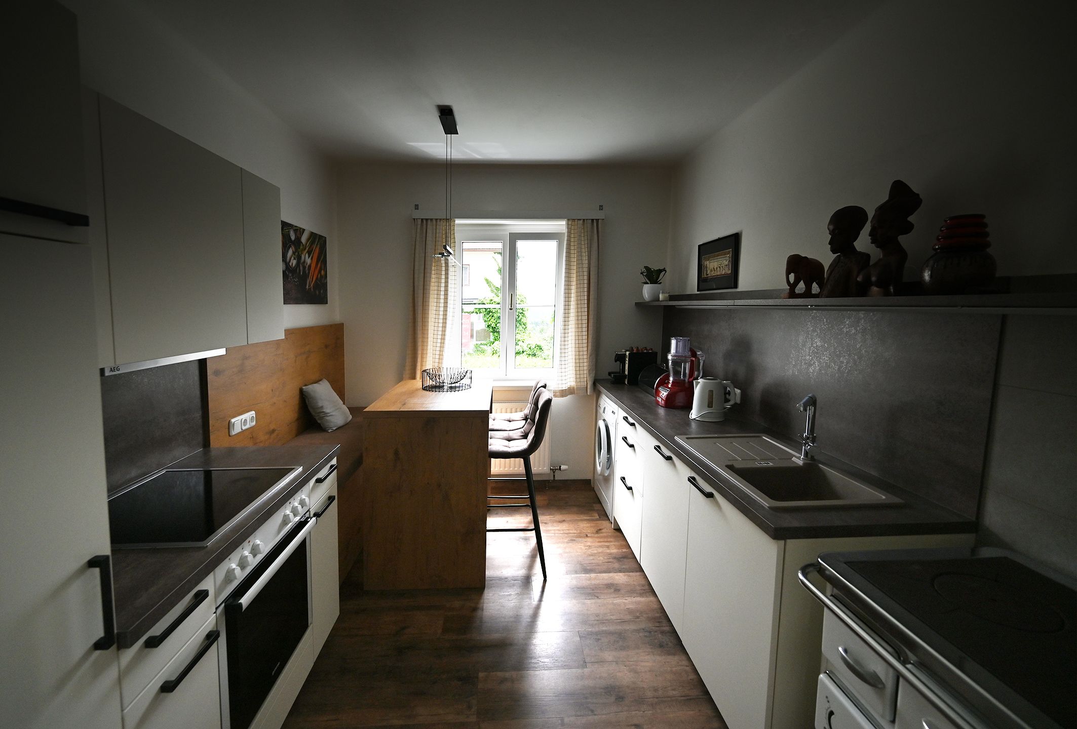 Modern kitchen with wood and metal accents, dining table by the window, kitchen appliances and decorations on shelves.