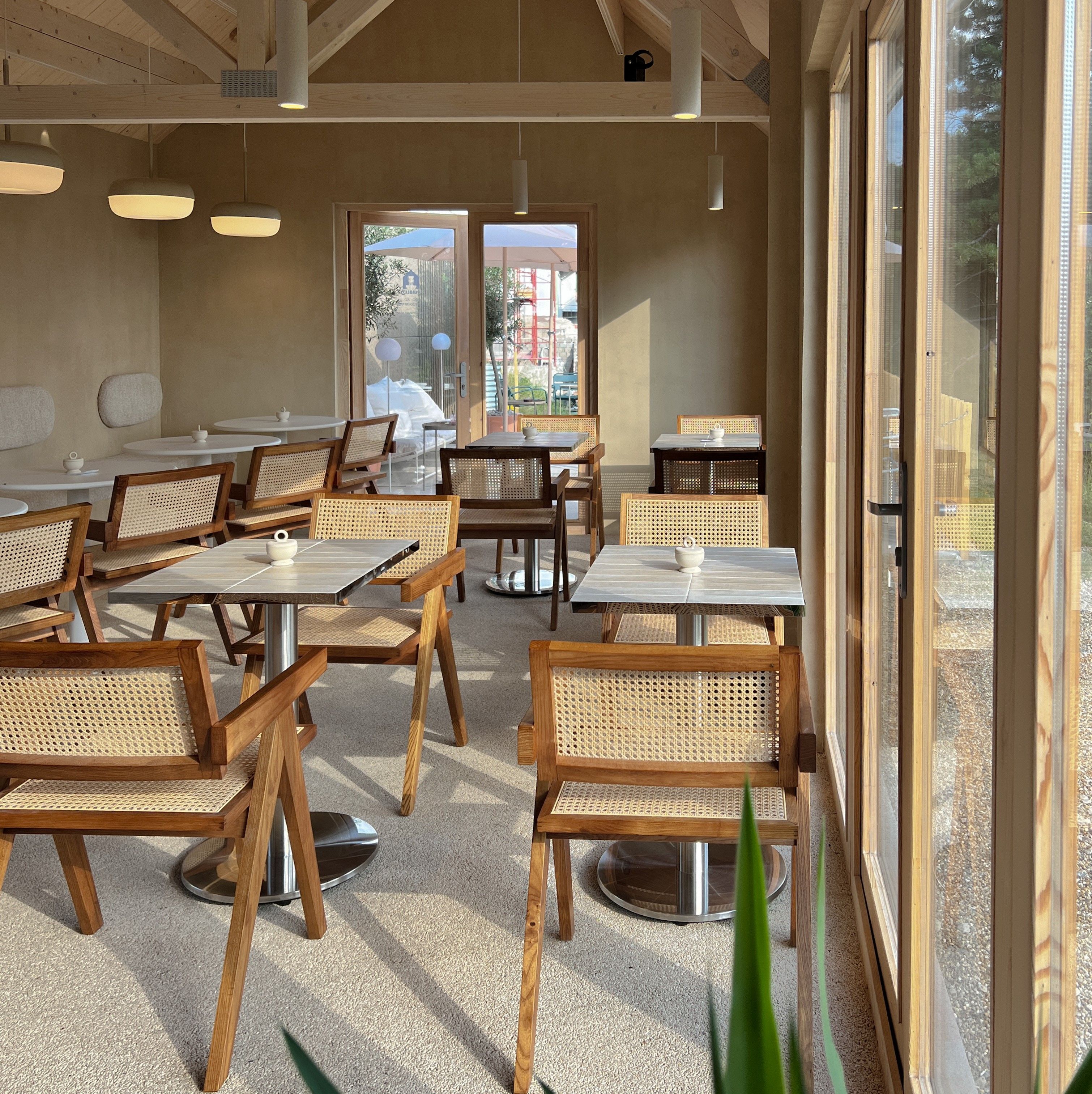 Interior of a café with wooden furniture and large windows.