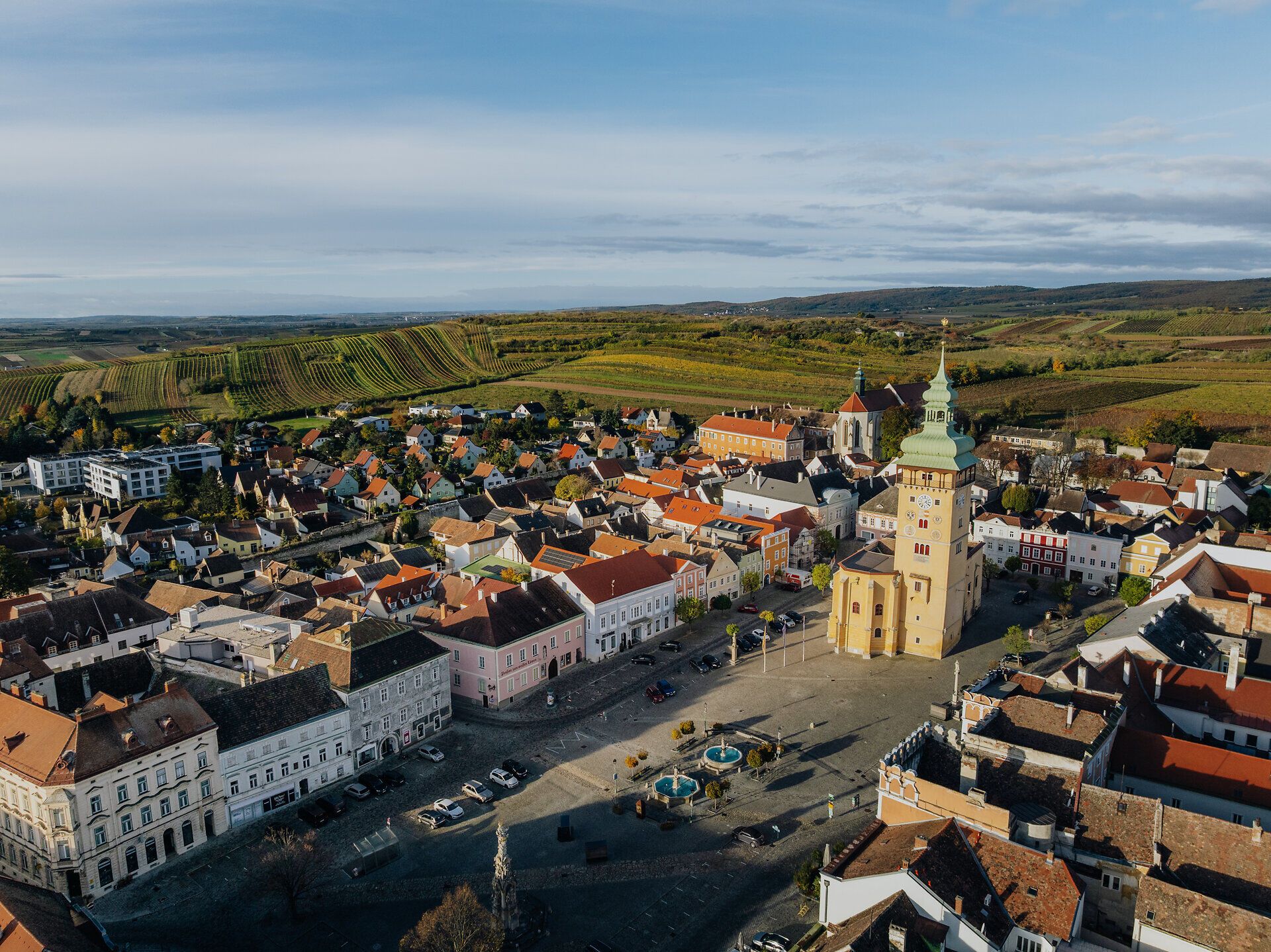 Der Retzer Hauptplatz mit seinen majestätischen Bauten und dem imposanten Rathausturm liegt eingebettet in die herbstliche Weinlandschaft des Retzer Landes.