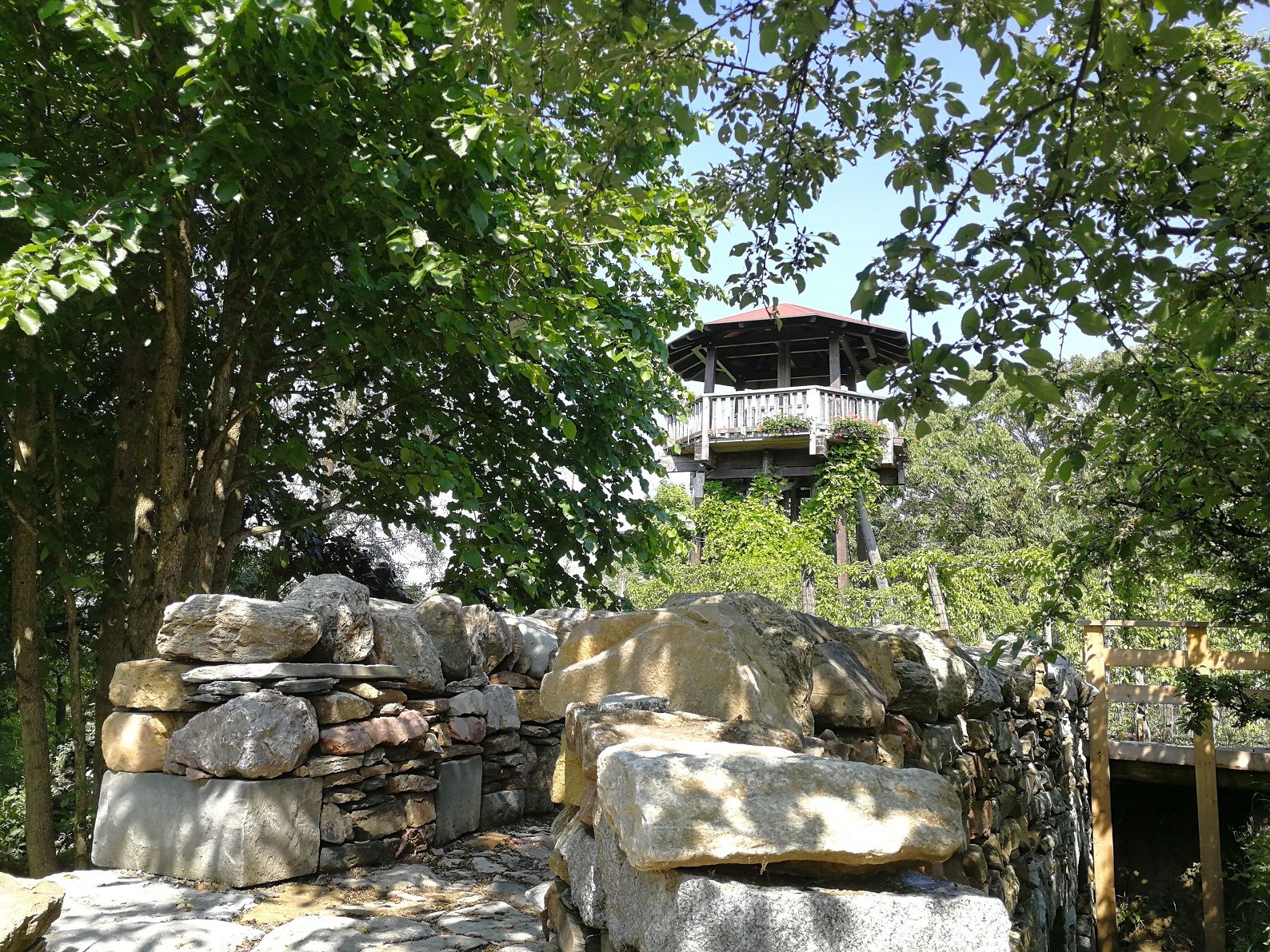 Observation tower of the Langenlois garden school surrounded by trees and a stone wall.