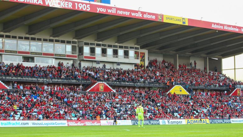 Soccer stadium with full stands and a player on the pitch.