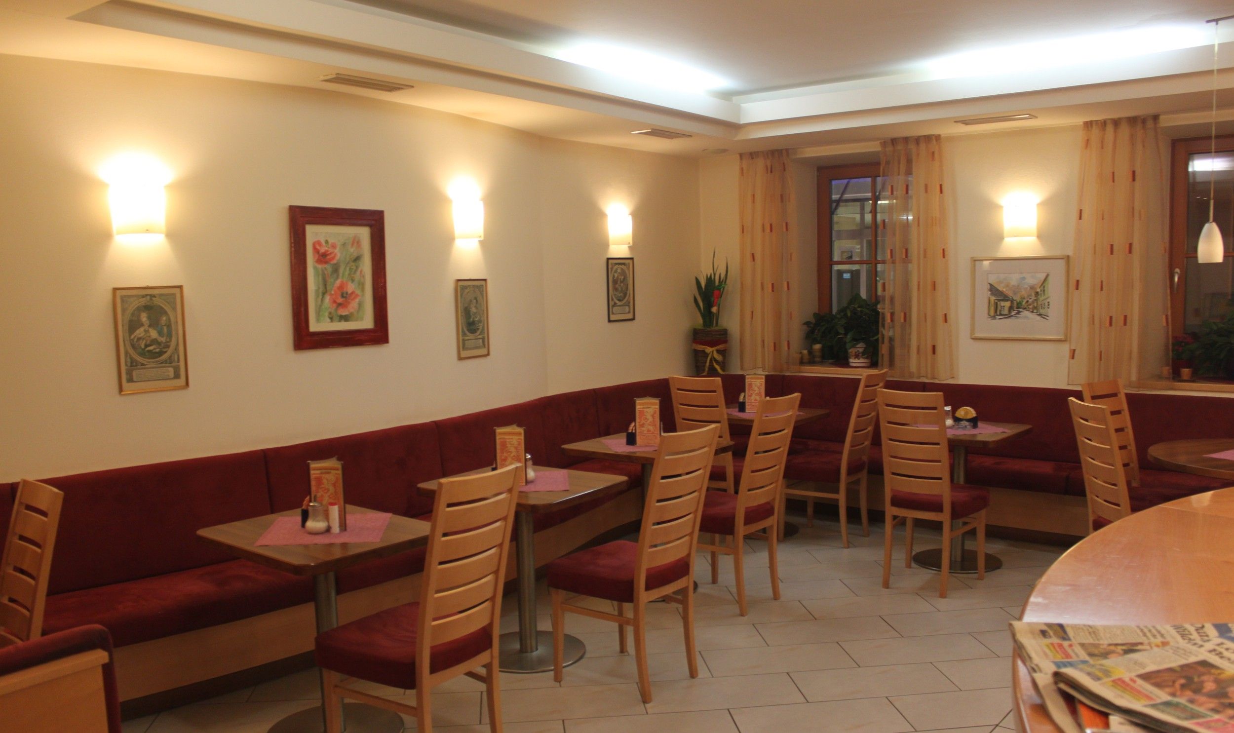 Interior view of a cozy café with red benches and wooden tables.