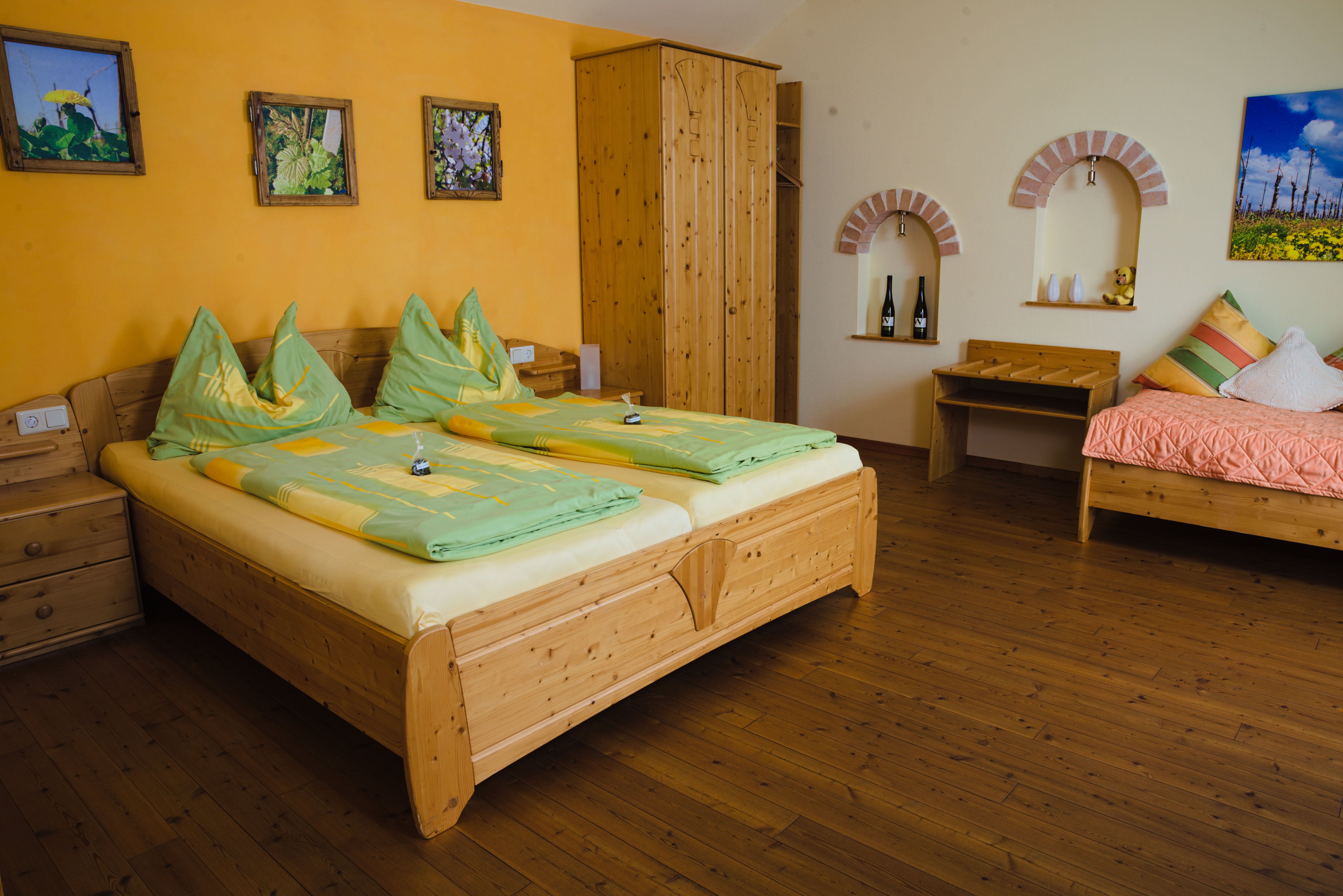 Cozy guest room with wooden furniture, double bed, single bed and decorative pictures on the wall.