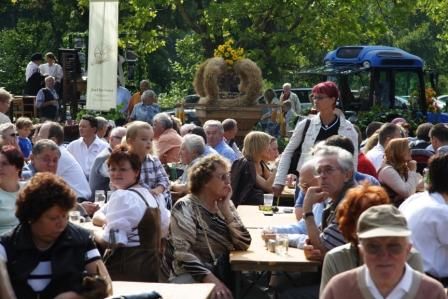 People sit at wooden tables at an outdoor party.