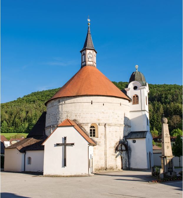 Scheiblingkirchen parish church with round tower and red roof against a blue sky.
