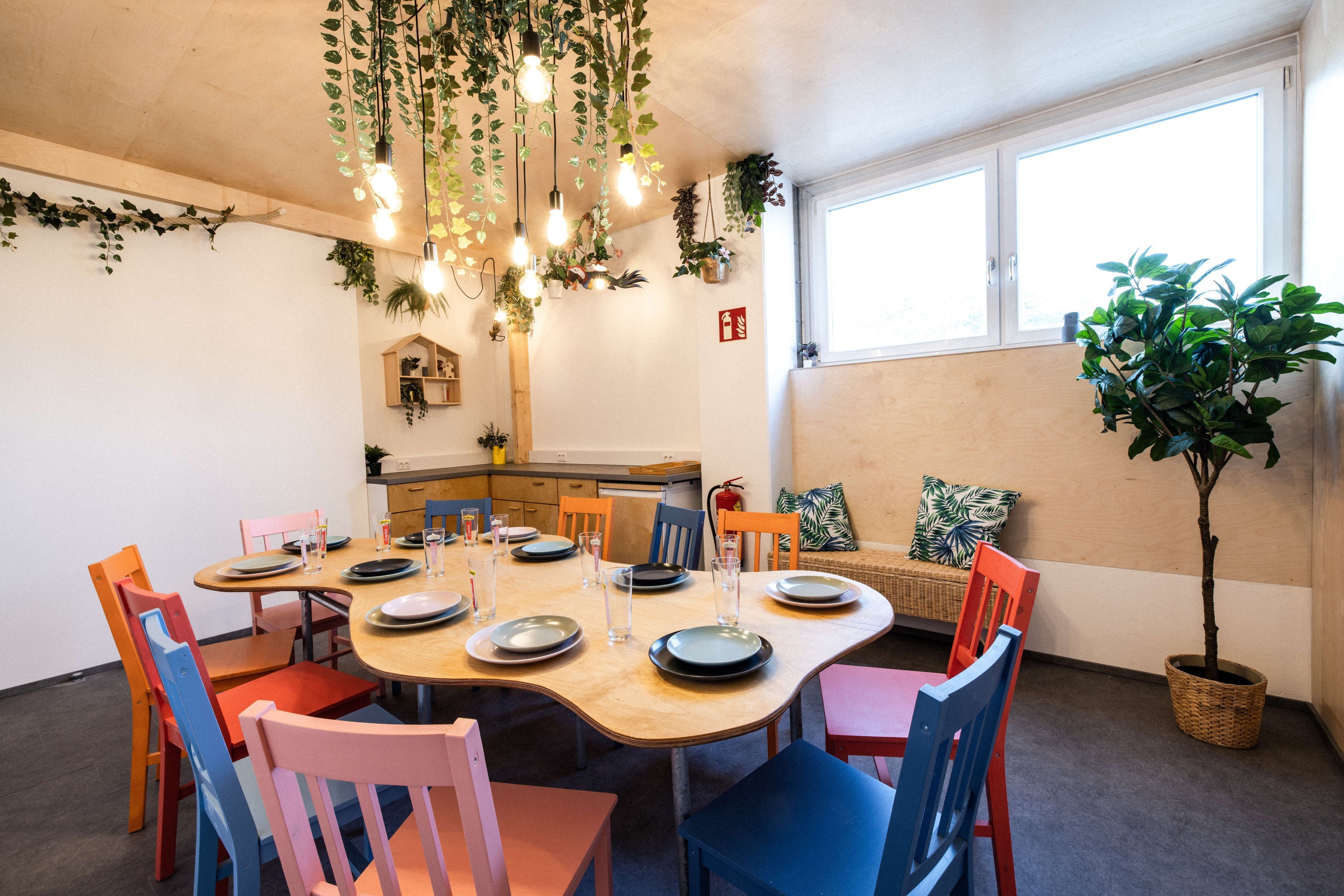 A cozy room with a table surrounded by colorful chairs and plants.