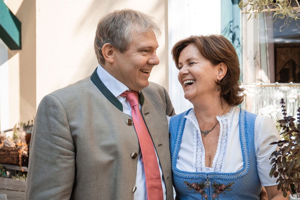 A man and a woman in traditional Bavarian dress laugh together.
