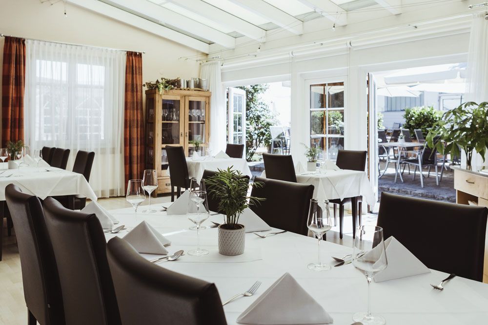 Elegant restaurant with white tablecloths and glass front facing the terrace.